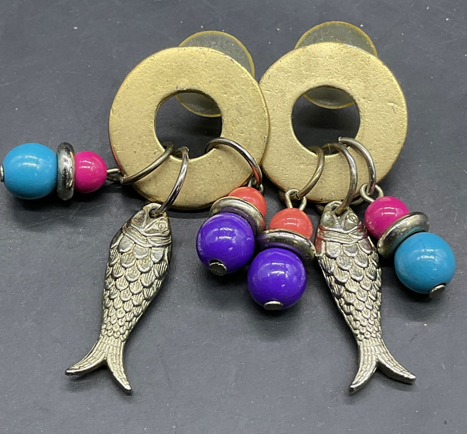 Vintage Fish Motif Beaded Disc Drop Earrings: Vintage Fish Motif Beaded Disc Drop Earrings. Crafted from metal and composite materials. Dangling fish charms alongside colorful beads. Post backings. Measures approx. 1.75L x 1W in. Discoloration, l