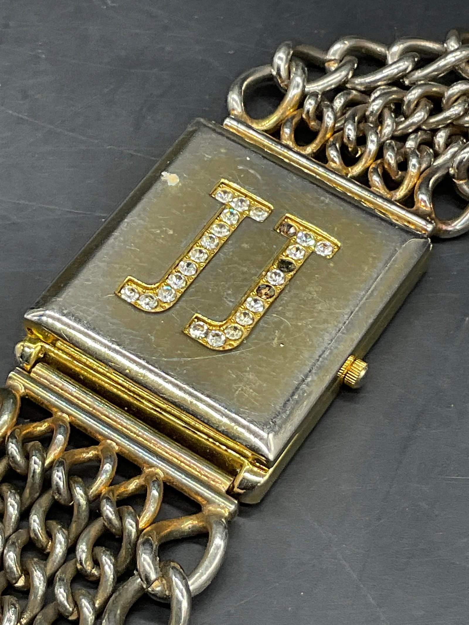 JJ Vintage Chunky Bejeweled Gold Tn Metal Watch: JJ Vintage Chunky Bejeweled Gold Tone Metal Watch Bracelet. Curb chain accents with a clasp closure to secure the watch. Top opens to reveal watch beneath the lid which reads JJ. Watch face reads JJ Q