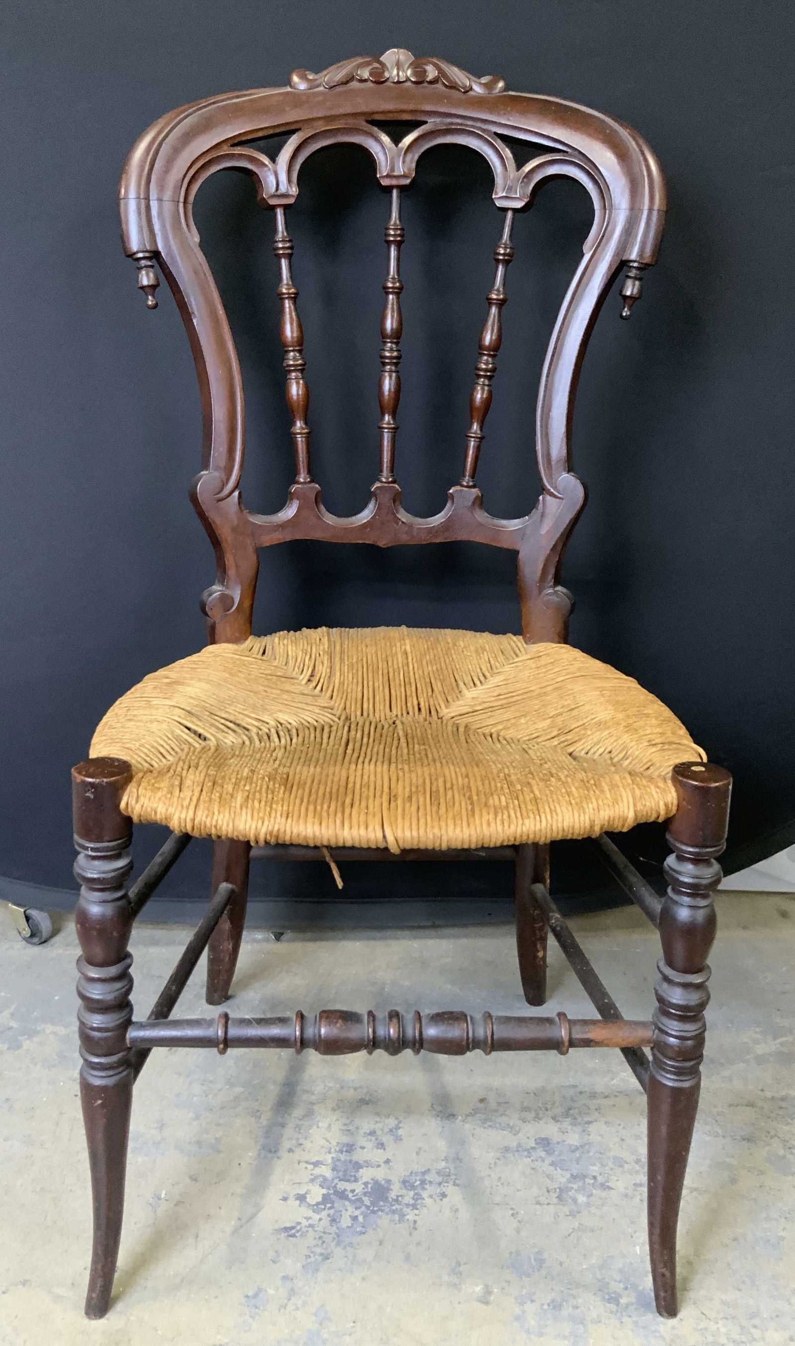Vintage Wooden Chair W Rattan Seat: Chair is vintage and wooden. Piece has tan toned woven rattan set. Chair frame is brown toned with intricately carved detail. Chair legs have box stretcher in between. Measures approximately 35 inches