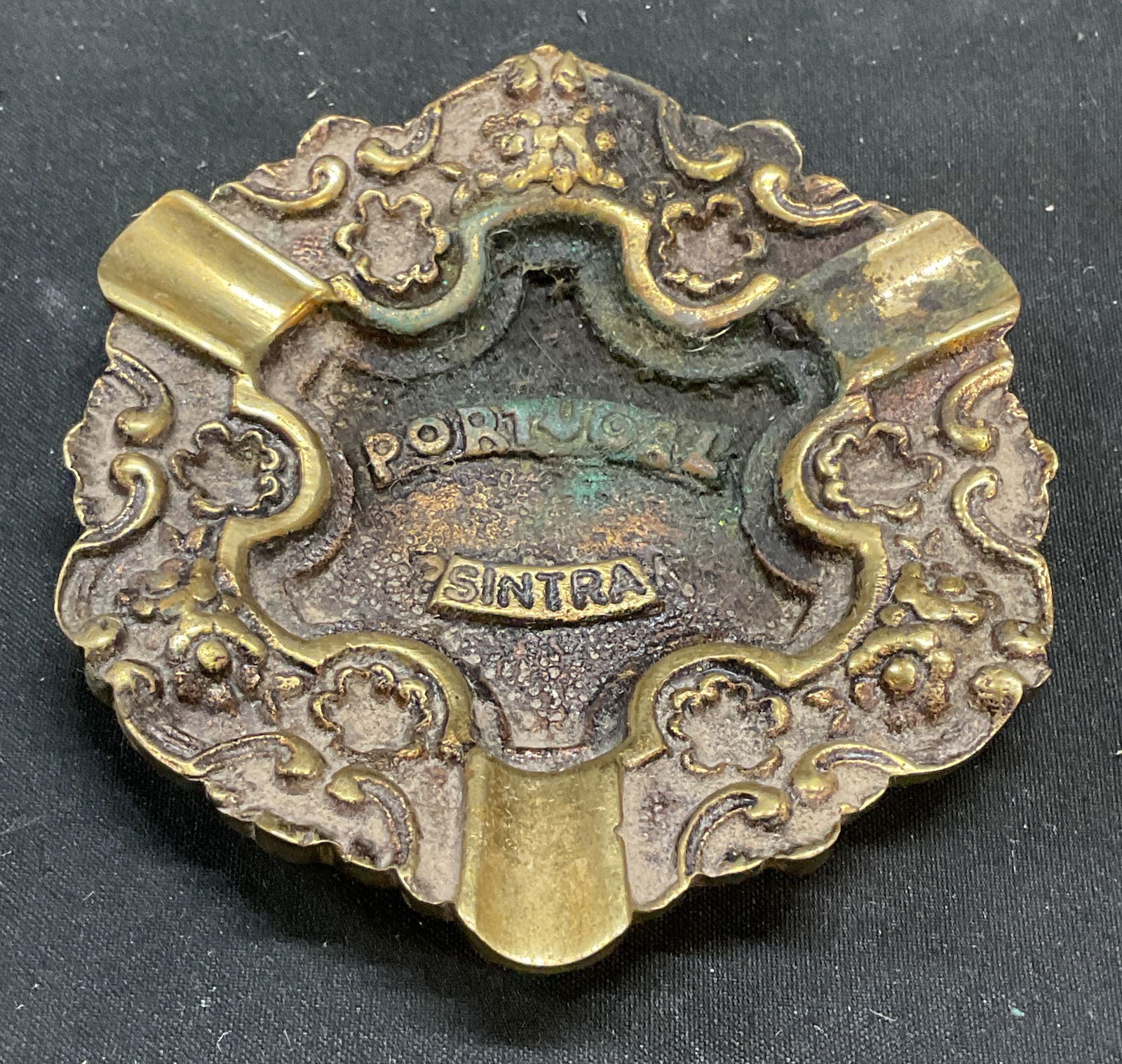 Vintage Brass Portugal Sintra Souvenir Ashtray: Vintage brass souvenir ashtray. Reads Portugal Sintra. Raised floral scroll design. Measures approx 3.5 inches wide. Some patina and scratching observed. Ashtray, brass ashtray, vintage ashtray, souve