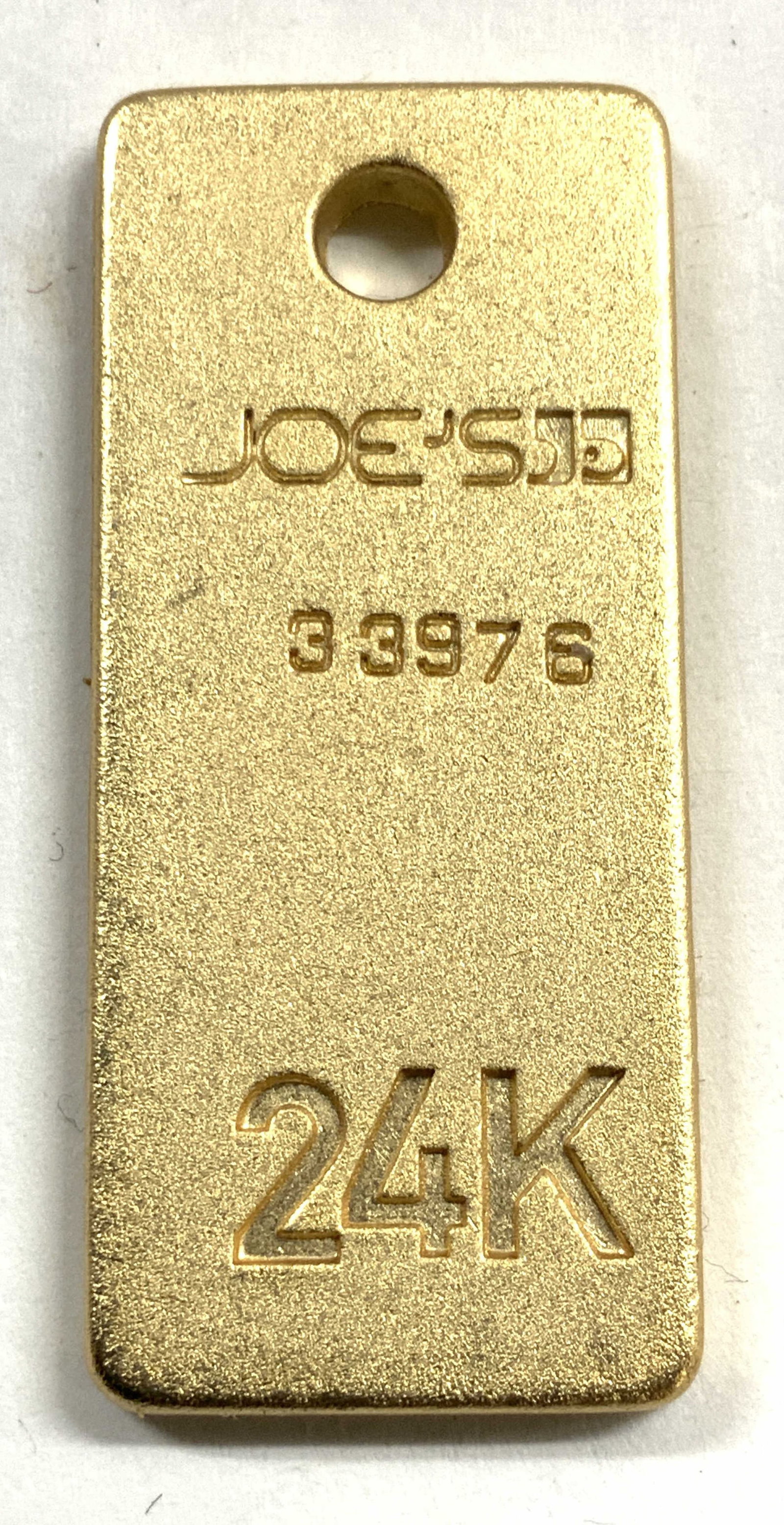 JOES 24K Gold Plated Pendant: Pendant reads JOES 33976 24K. Pendant has rounded rectangular form. Piece is gold plated. Piece measures approximately 1.5 inches long .5 inches wide. Pendant, 24 karat gold plated pendant, Joes penda