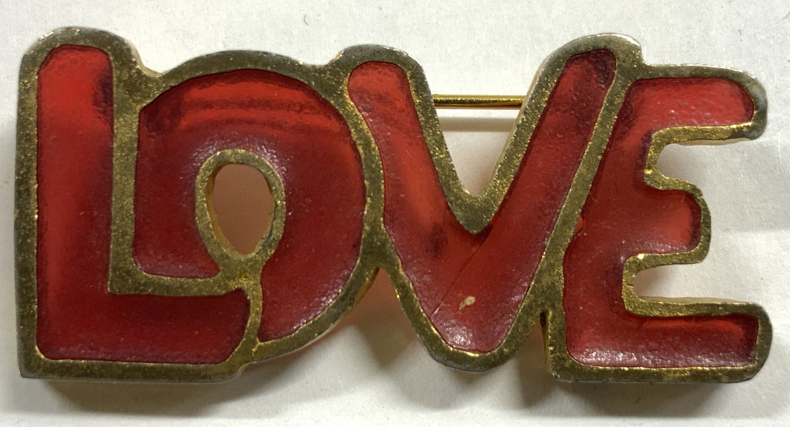 JOY LOVE Enamel & Gilt Brooch Pin: Side of letter L is signed JOY. Brooch pin reads LOVE. Piece is red toned enamel with gilt edges. Brooch pin measures approximately 1.75 inches wide .75 inches tall. Pin, brooch pin, Love brooch pin,