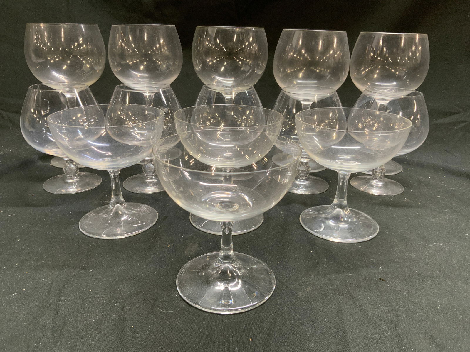 Lot 14 Assorted Crystal Cocktail Glasses: Lot includes 5 wine glasses, 5 brandy snuffers, & 4 champagne glasses. Each piece appears to be crystal. Wine glasses measure approximately 7.25 inches tall 4 inches wide. Wine glasses, cocktail glass