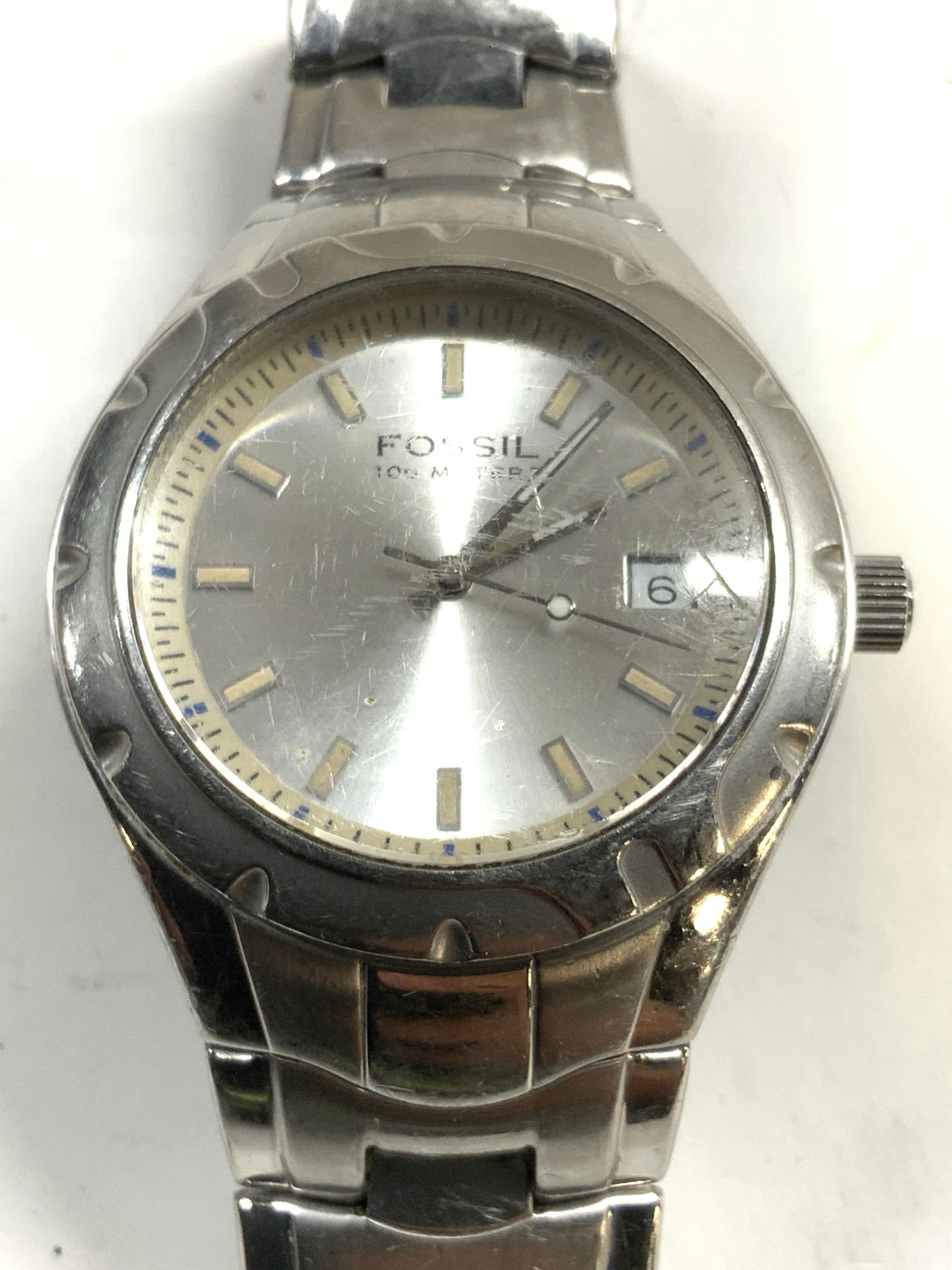 FOSSIL Stainless Steel Wristwatch Push Button Clsp: Watch face reads FOSSIL 100 METERS. Watch is silver toned stainless steel. Watch has push button clasp on band. Backside of face reads fossil blue. Watch measures approximately 1.75 inches wide 6.5 in