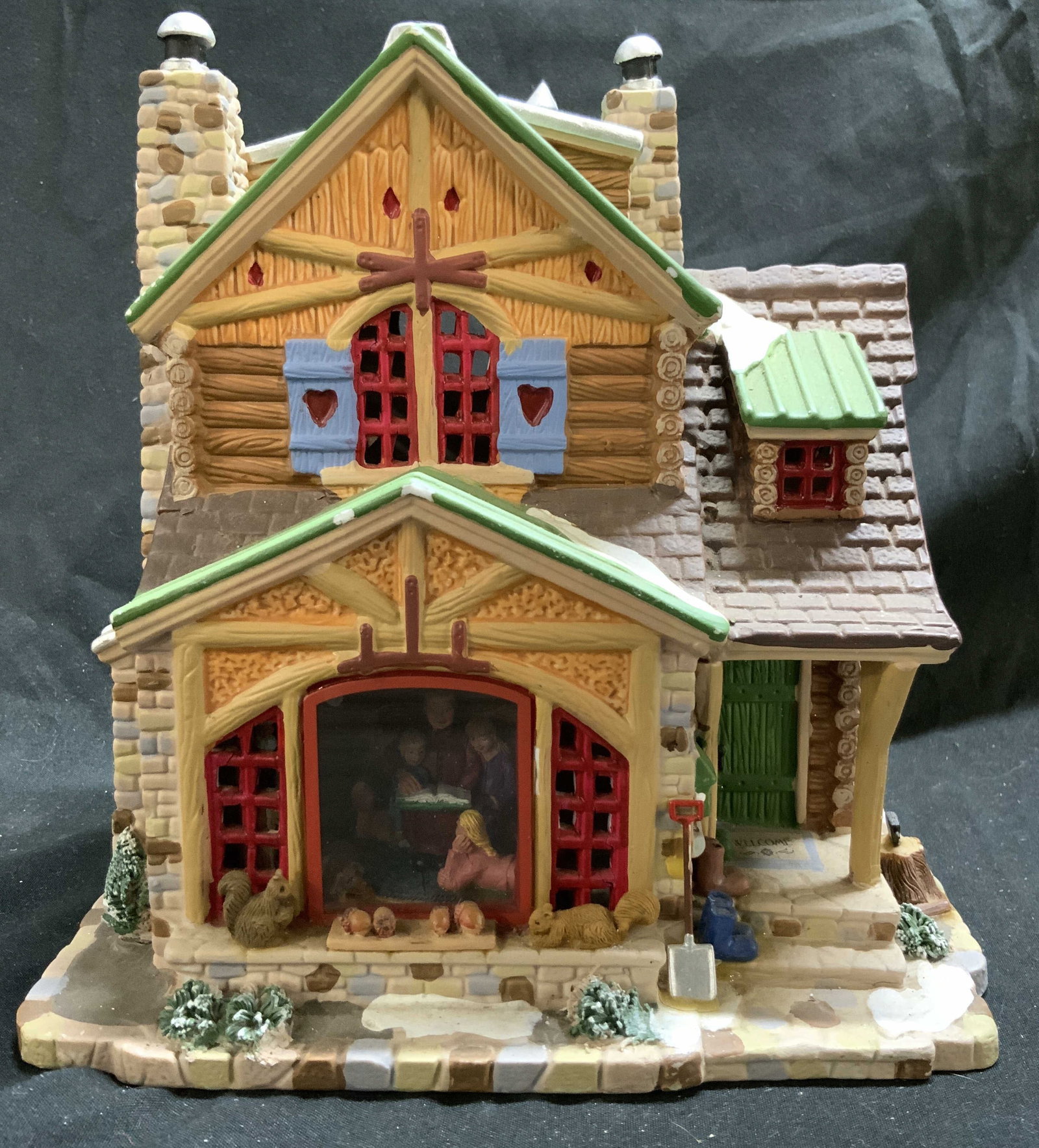 Lemax Vail Village Coll Cozy Cabin #05077: Underside is inscribed LEMAX. Piece is porcelain. Depicts a cabin with family inside reading a story. Lemax Vail Village Collection Cozy Cabin Lighted Building #05077. Piece measures approximately 7.5