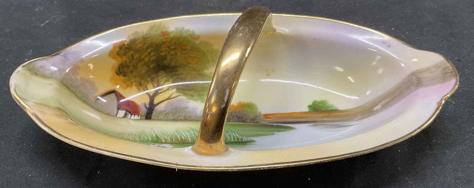 Vtg Nippon Hand Painted trinket Dish with Handle: Vintage Nippon hand painted trinket dish with handle. Scenic landscape design. Porcelain. Signed on underside. Diagonal handle design. 8.5 x 4 inches. Some surface wear consistent with exposure. Nippo