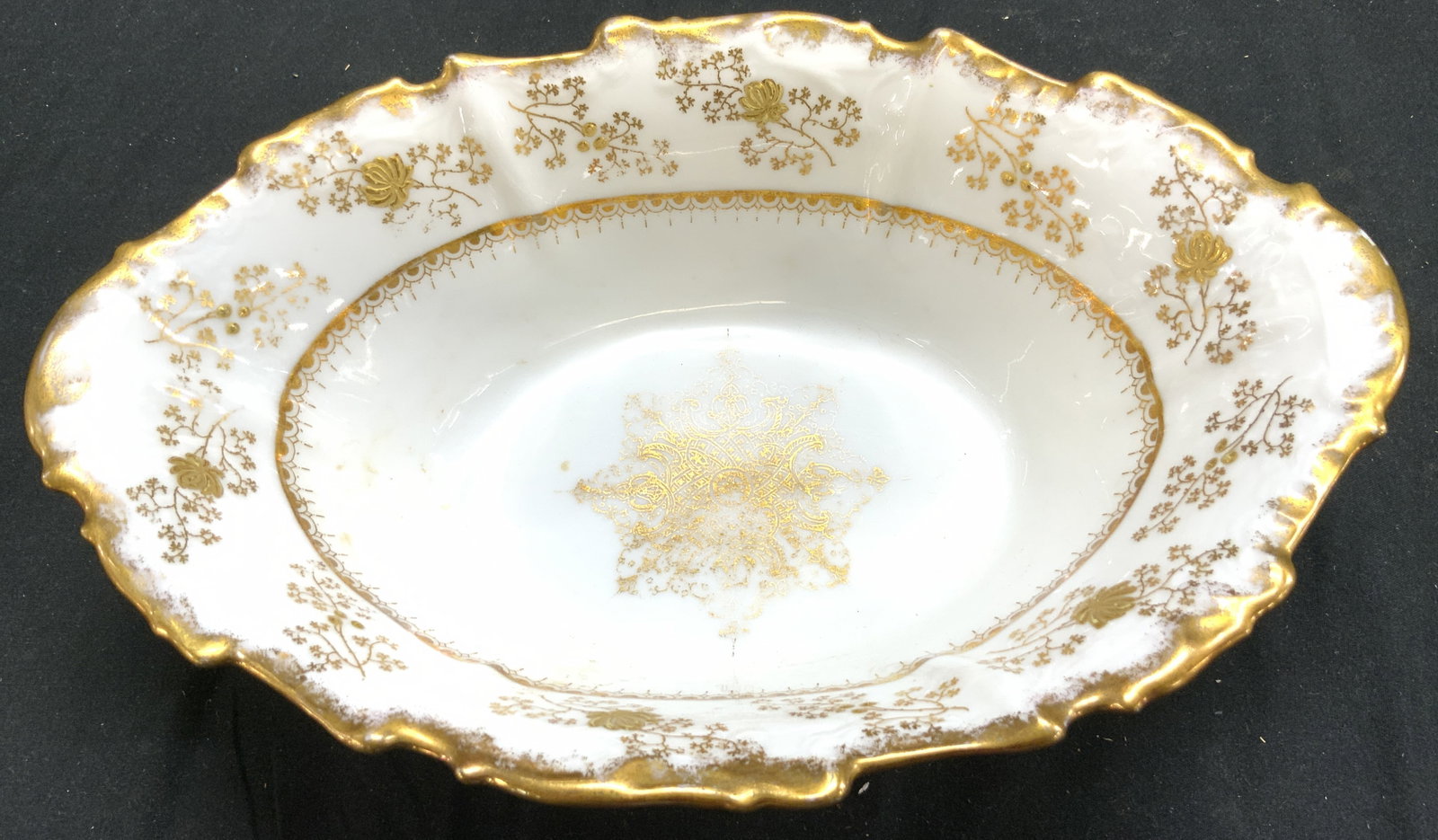 LIMOGES FRANCE Vntg Gilt Porcelain Serv Bowl: Underside is marked LIMOGES FRANCE. Serving bowl is white with gilt floral and leaf detail. Bowl is porcelain and has gilt rim. Rim has irregular edges. Vintage French porcelain. Bowl measures approxi