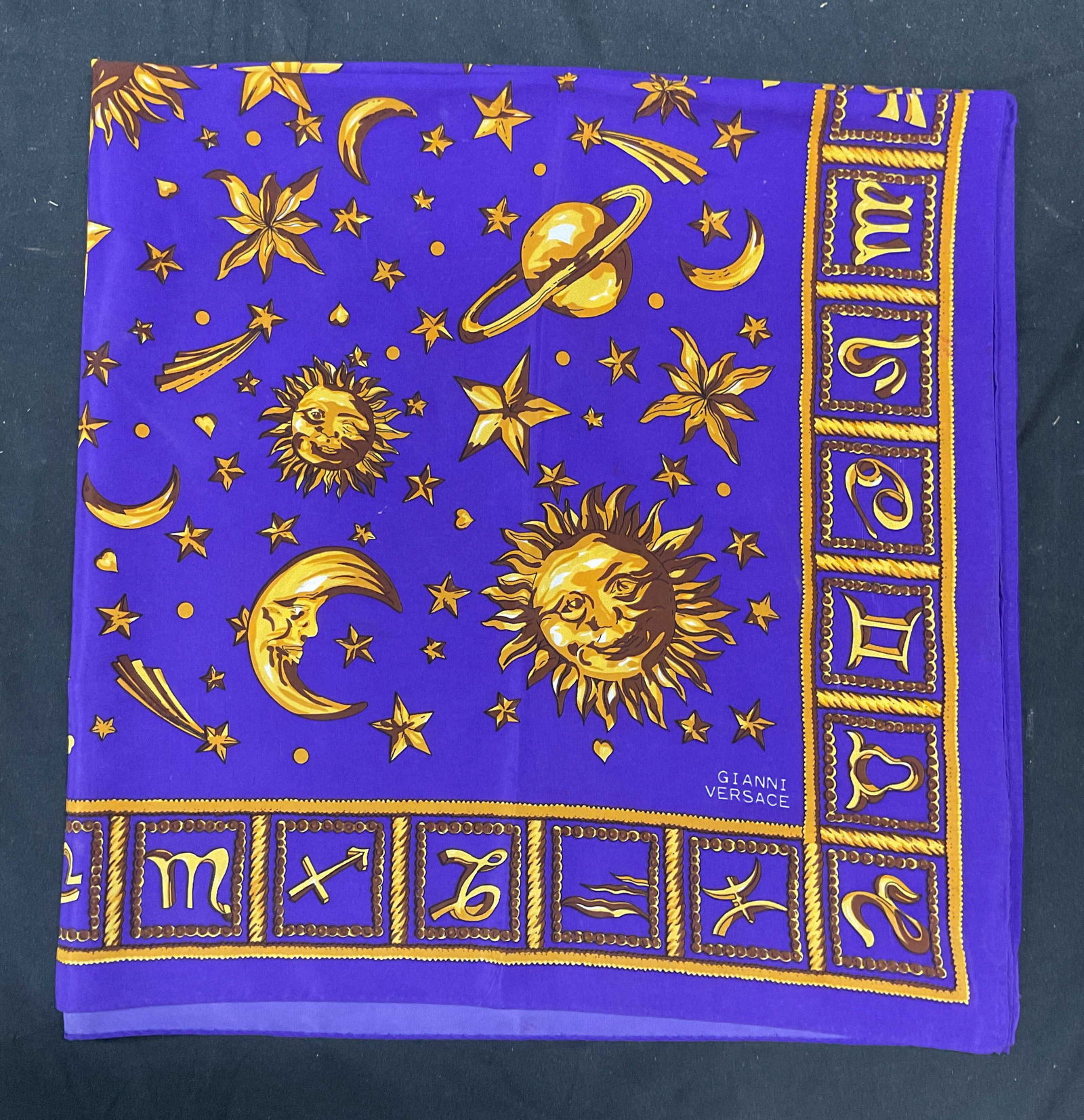 Purple Gold Silk Celestial Zodiac Print Scarf: Purple and gold celestial and zodiac print scarf. Feels like silk. Measures approx 34 x 34 inches. Some wear including pulling and blemishes observed. The Benefit Shop does not guarantee authenticity