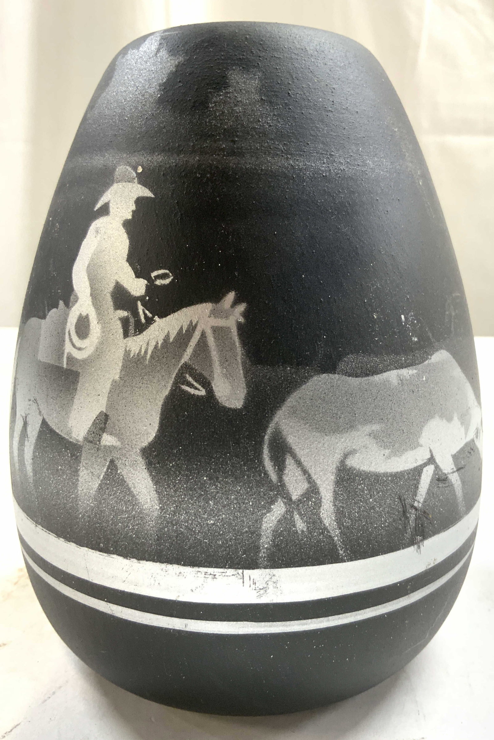 DINE Signed Vtg Native American Southwest Vase: Underside is signed DINE. Native American southwest pottery vase. Piece is black with silver toned depictions of a figure riding horseback following a steer. Vessel appears to be vintage. Piece measur