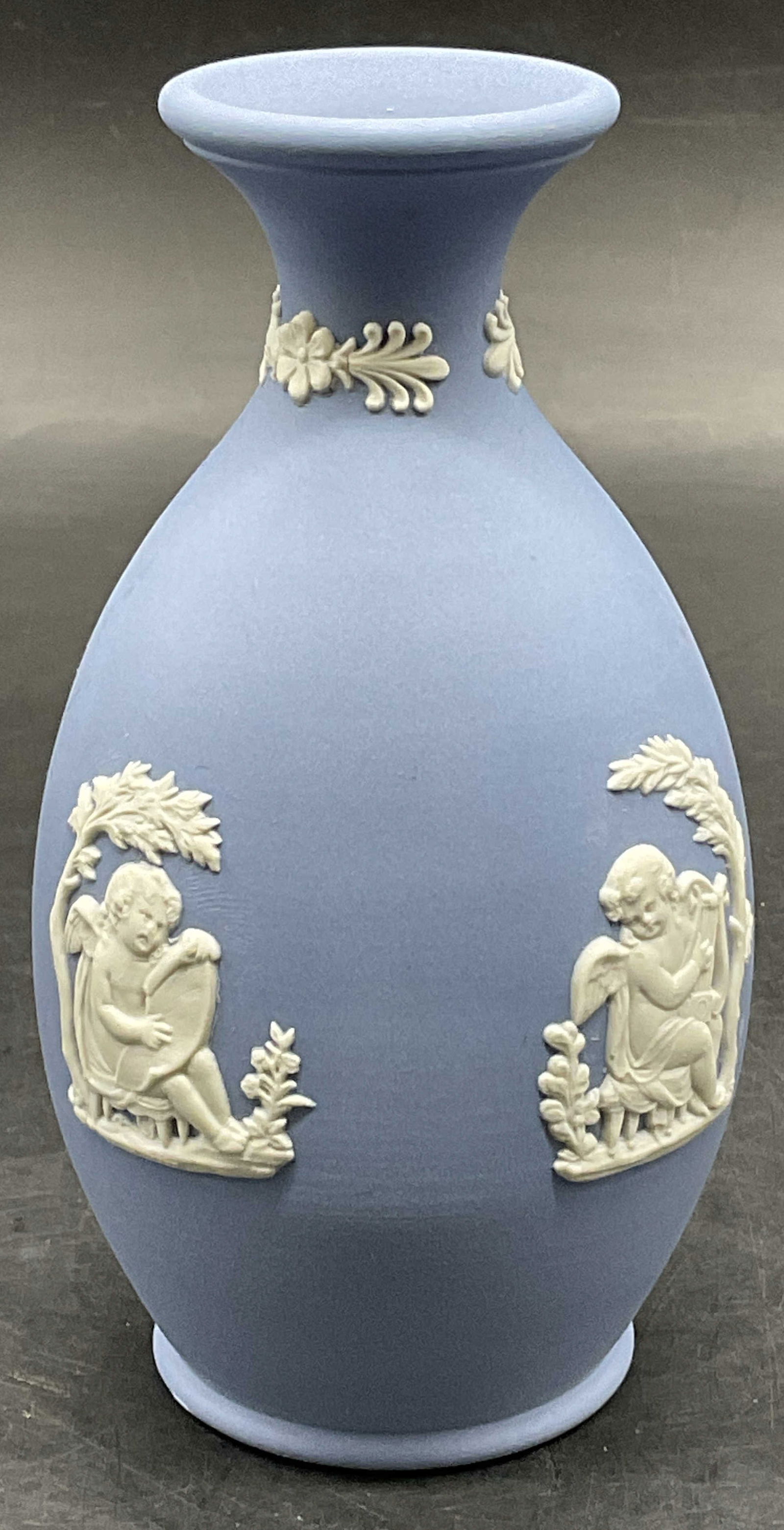 WEDGWOOD ENGLAND Vntg Blue Jasperware Vase: WEDGWOOD ENGLAND Blue Jasperware Bud Vase. A vintage Wedgwood Jasperware bud vase, featuring neoclassical scenes in white bas-relief against a pale blue background. Measures approx. 5H x 2.5W in. Meas