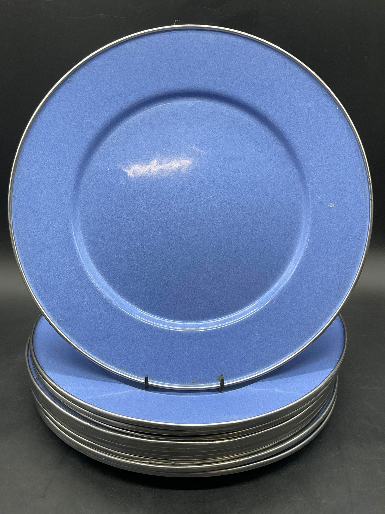 Set 11 Metal Enamelware Dinner Plates: Set of eleven blue-purple hued metal enamelware dinner plates. Silver tone metal rims. Measures approx. 10.75W x 10.75L in. Discoloration, residue, denting, and surface wear present. home decor, home