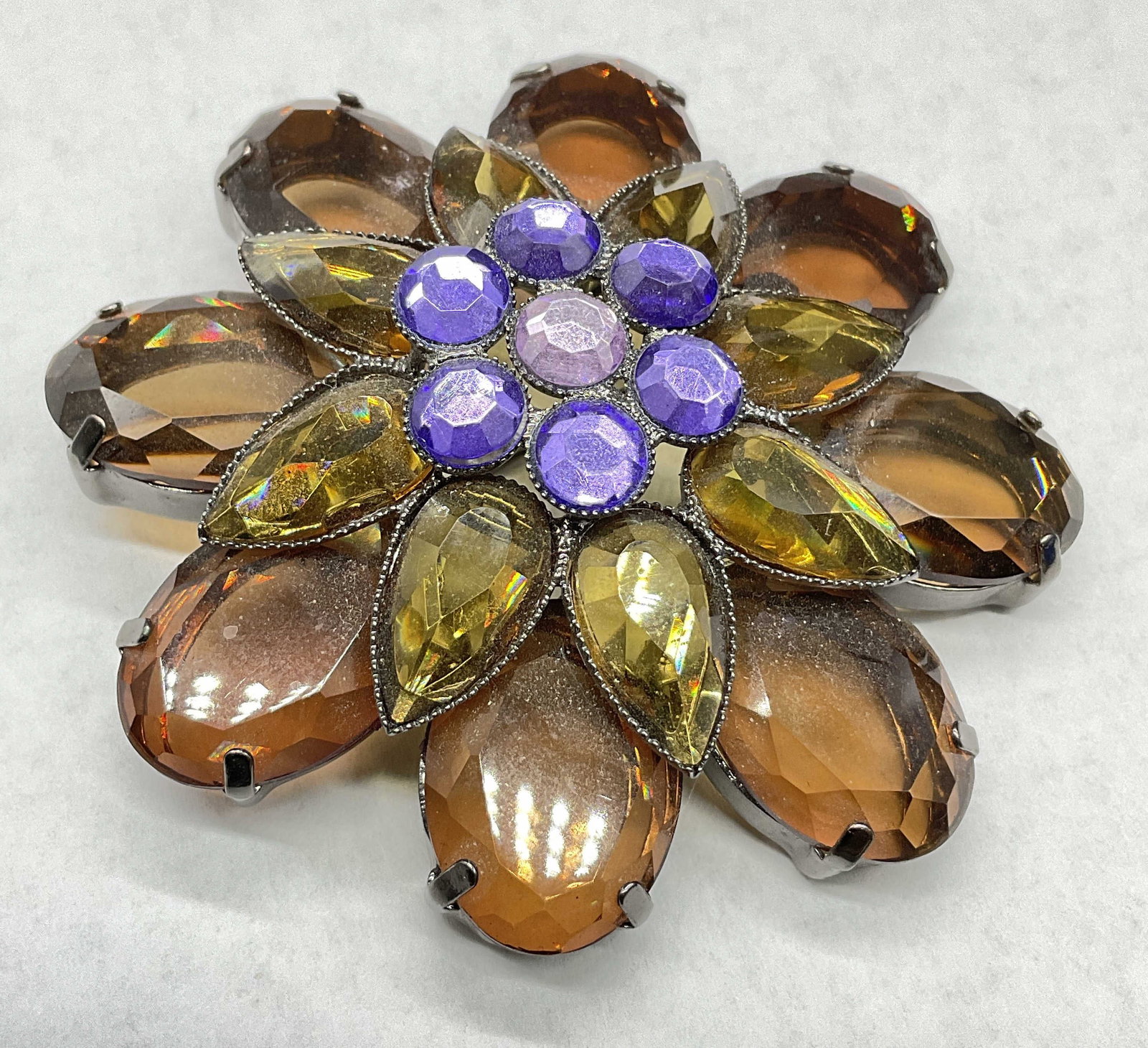 Vintage Crystal Floral Form Brooch: Vintage Crystal Floral Form Brooch. Faceted and amber hued crystals to the piece. Metal pin closure to reverse. Measures approx, 2.5W x 2.5L in. Warping to metal. Pin closure needs repair or replaceme