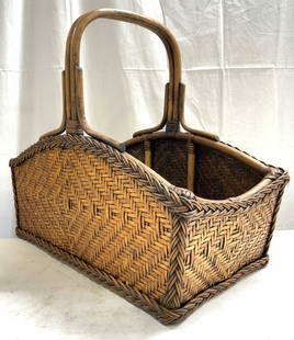 Vtg Woven Wicker Magazine Basket W Handle: Magazine basket is woven wicker/ rattan. Piece is tan toned and has handle in center. Basket appears to be vintage. Piece measures approximately 18.5 inches tall 21.5 inches deep 10.5 inches wide. Bas