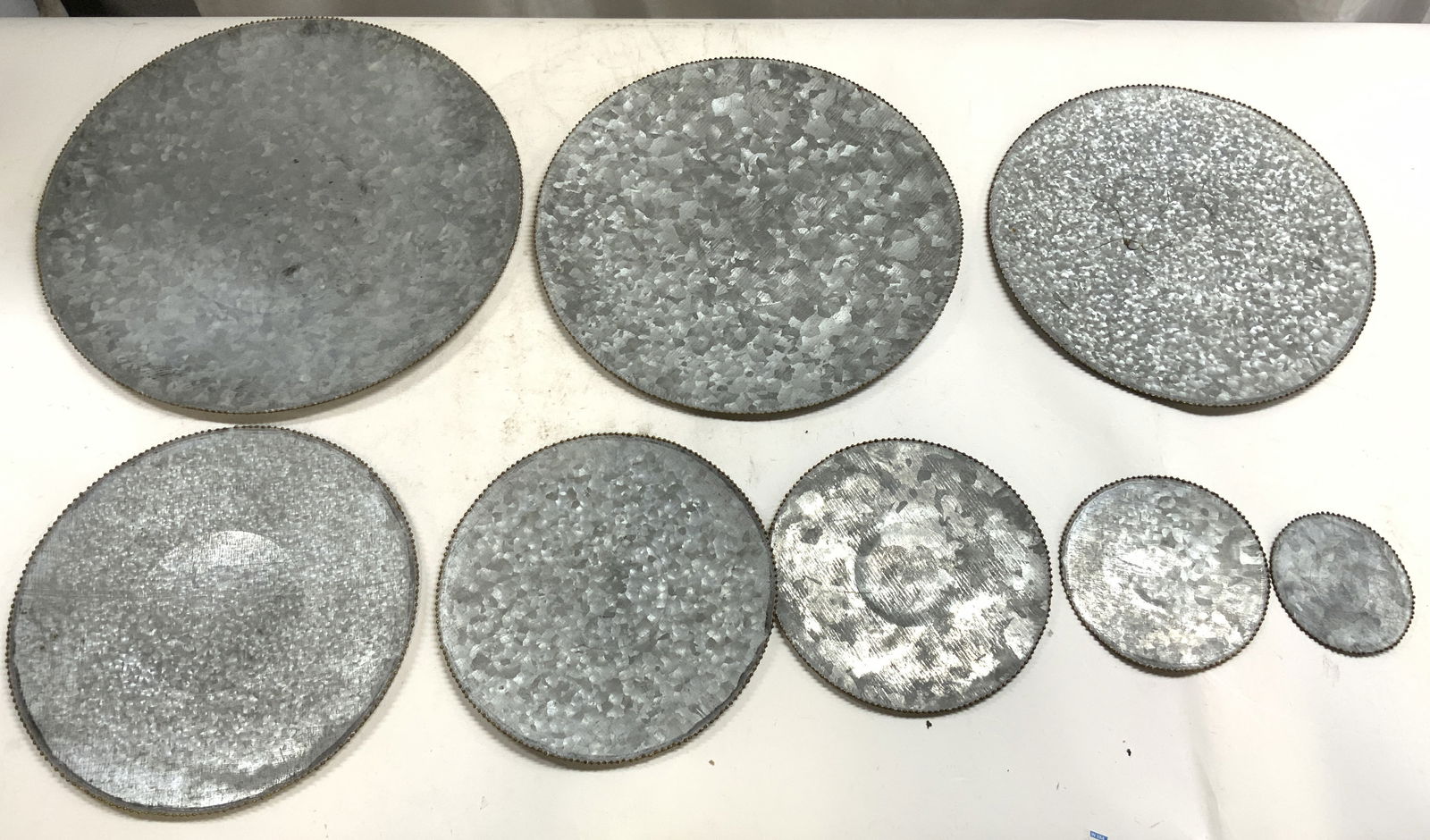 Set 8 Vtg Galvanized Metal Decor: Lot includes 8 Circular form decorative objects. Each are silver toned galvanized metal with beaded edges. Pieces appear to be vintage. Largest piece measures approximately 15 inches diameter. Galvani