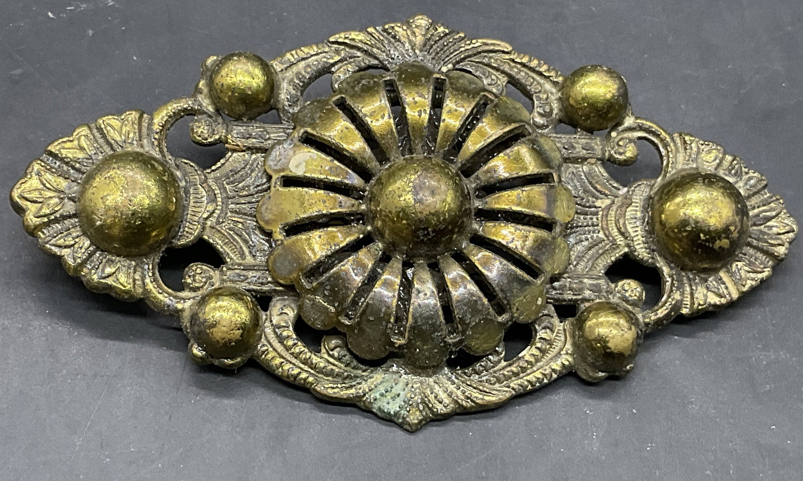 Vintage Brass Toned Metal Floral Motif Brooch: Vintage Brass Toned Metal Floral Motif Brooch. Raised metalwork designs. Metal pin closure to reverse. Measures approx, 3W x 1.5L in. Warping to metal. Pin closure needs repair or replacement. Surface