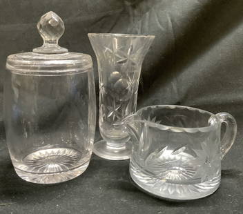 Lot 3 Art Glass Tabletop Accessories: Lot includes 1 footed vase, 1 creamer dish, & 1 jar with lid. Creamer dish has floral and leaf detail. Jar measures approximately 6.25 inches tall 3.5 inches wide. Art glass, glass tabletop, vase, ves