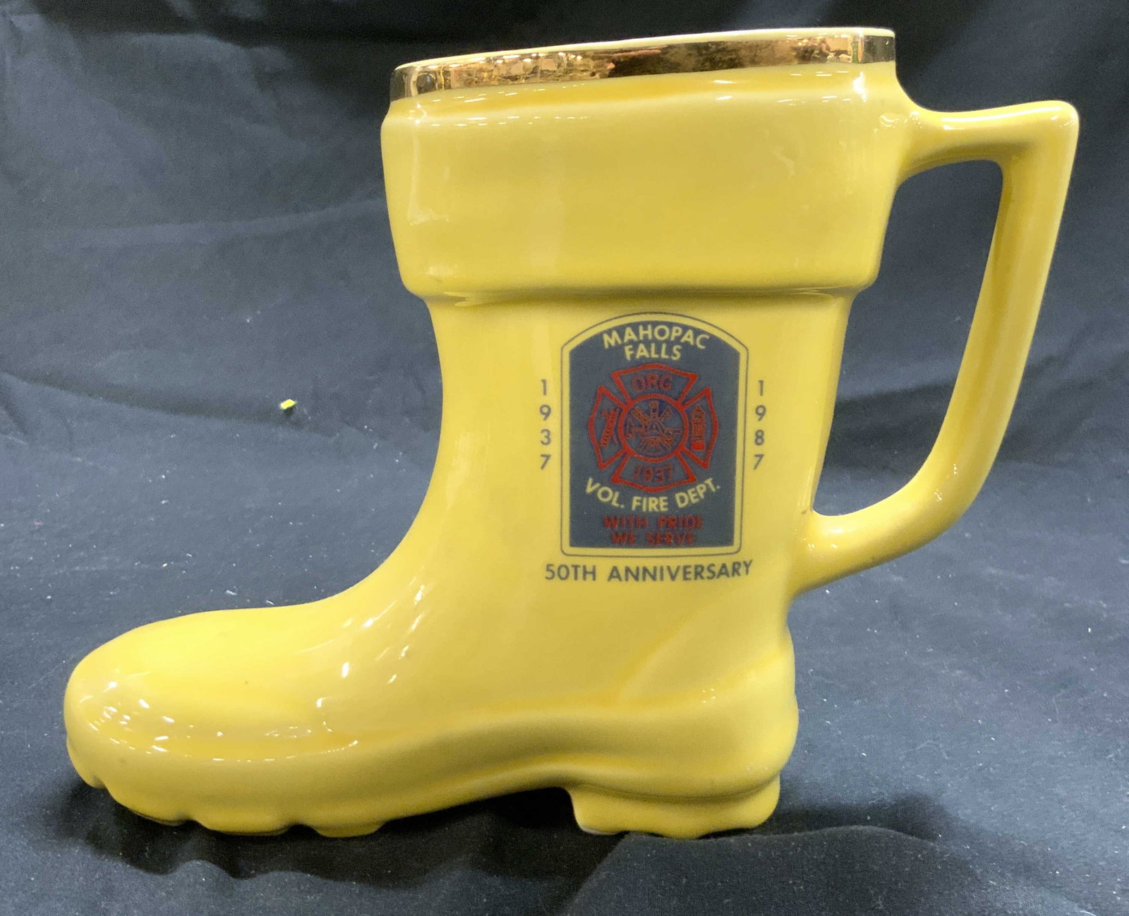 SUNSET Vtg Mahopac Falls Porc Fireman Boot Mug: Underside is trademarked SUNSET side reads MAHOPAC FALLS 1937 1987 VOL FIRE DEPARTMENT. Mug is yellow toned with gilt rim. Piece has fireman boot form. Vessel with handle measures approximately 10 inc