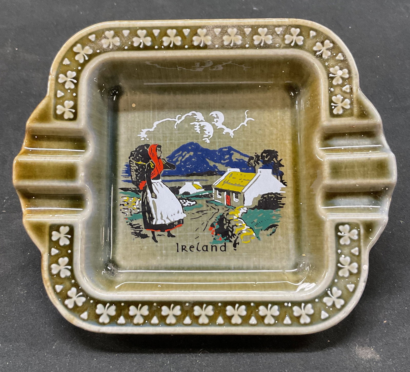Vtg Wade Irish Porcelain Ashtray Ireland: Vintage Wade Irish Porcelain ashtray. Irish countryside scene with a woman and cottage. The word Ireland printed on bottom. Rim decorated with embossed chat rocks. 4 cigarette rests. Made in Ireland. 