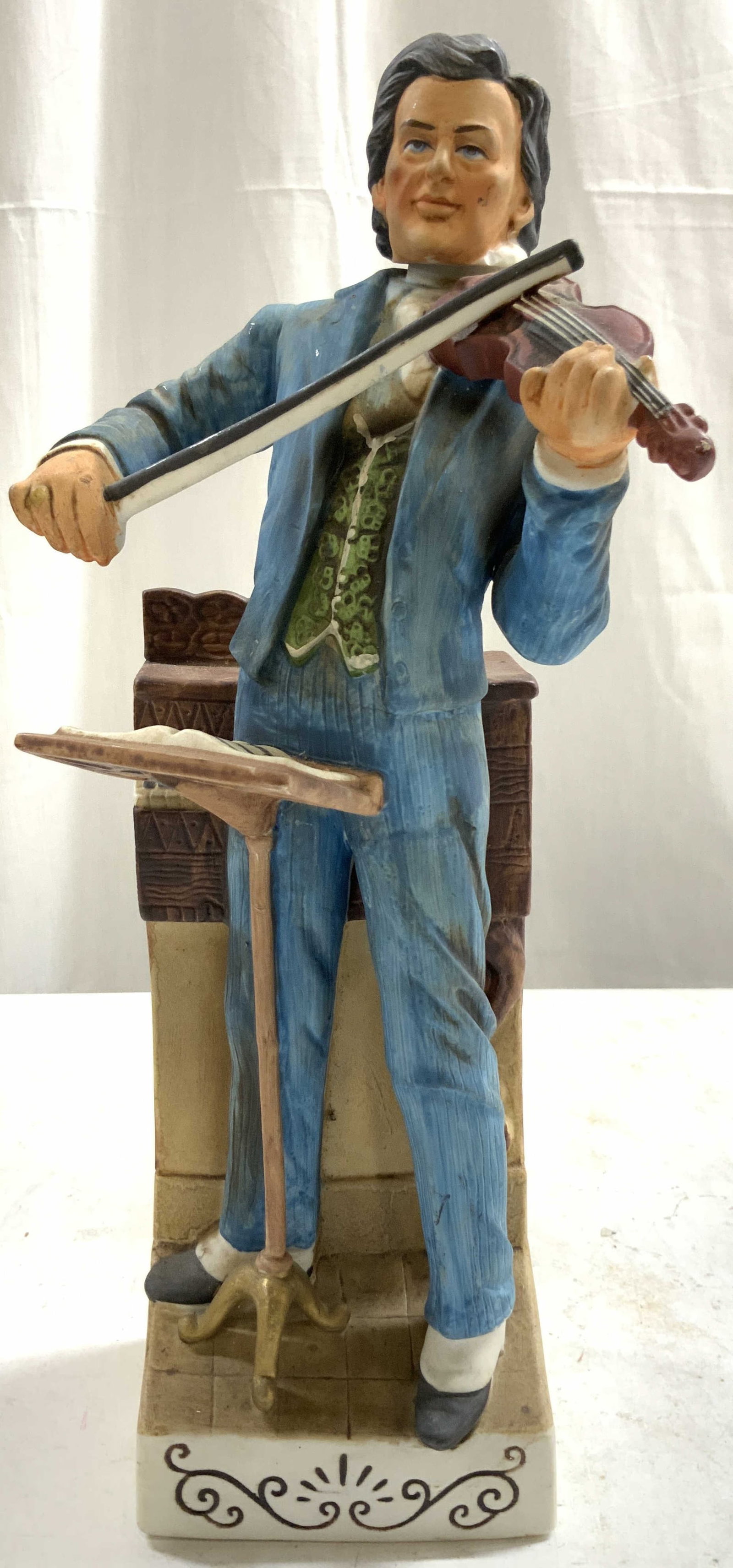 Cyrus Noble Haas Bros The Violinist Whsky Decanter: Backside reads COMMEMORATING CYRUS NOBLE MINE. Decanter is vintage. Piece depicts a standing male figure playing the violin wearing a blue toned suit. Decanter appears to be porcelain. Piece includes 