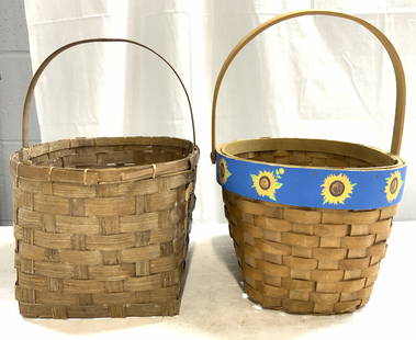 Lot 2 Vintage Woven Rattan Baskets: Lot includes 2 baskets. Each are tan toned woven rattan. Baskets appear to be vintage. Each piece has arch form handles. One basket has blue toned outer rim with green, yellow, & brown toned sunflower