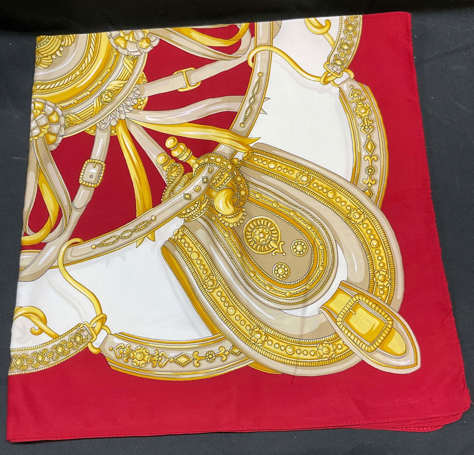 Red & Gold Equestrian Print Scarf: Red and gold scarf with equestrian motif print. Feels like silk, possibly synthetic. Measures approx 34 x 34 inches. Some blemishes observed. Scarf, equestrian scarf, red scarf, gold scarf, accessorie