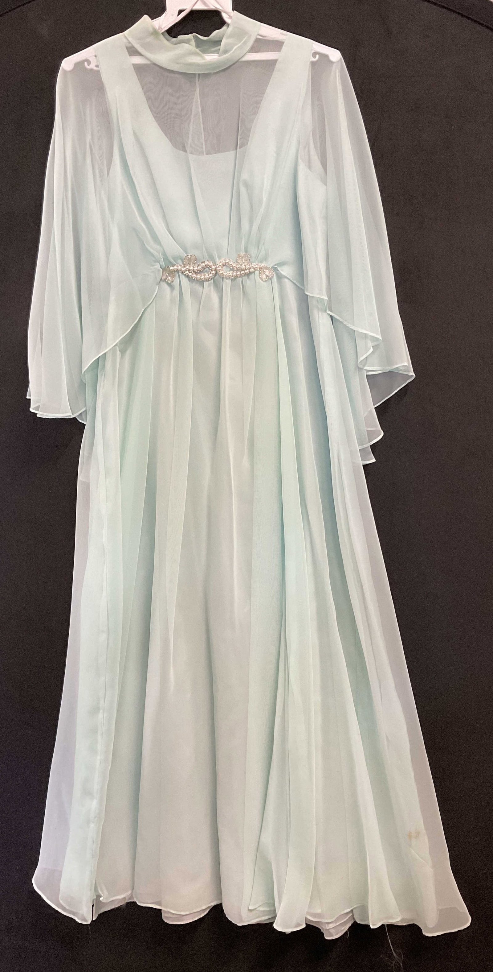 Vintage Caped Pearlescent Applique Dress: Vintage Caped Pearlescent Applique Dress. Light seafoam green hue. Cape can be latched and unlatched but is affixed to the dress. Zipper closure to the dress. Dress measured flat approx. 12 inches acr