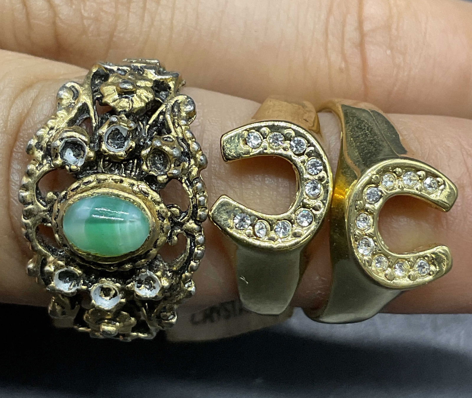 Lot 3 Bejeweled Metal Rings, Austrian Crystal USA+: Three bejeweled rings crafted from metal. Two rings have their original tags attached which read MADE IN USA, GENUINE AUSTRIAN CRYSTAL. Sizes on the tags appear to read 6 and 5. Larger Ring features a