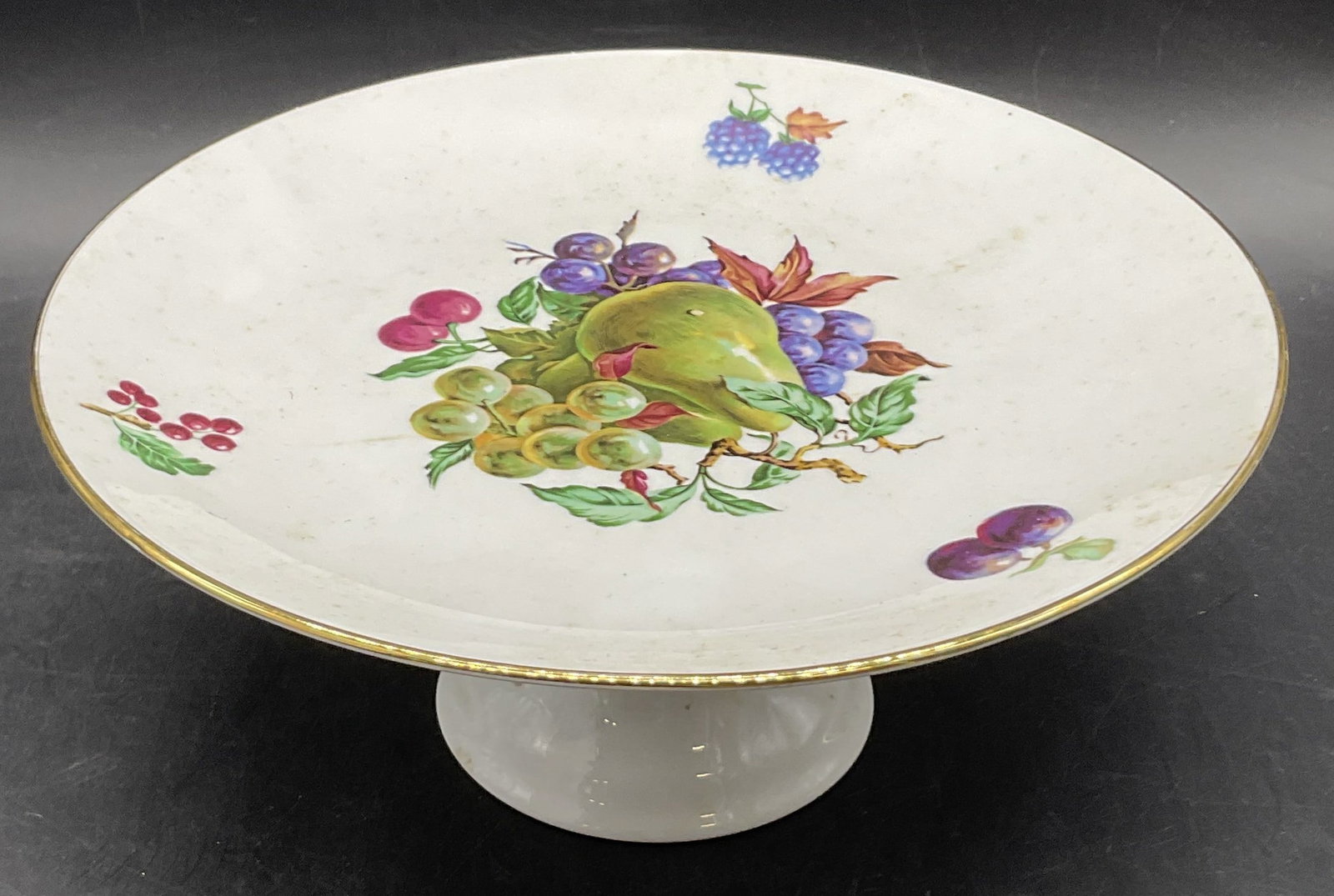 NAAMAN Vintage Porcelain Footed Cake Plate: NAAMAN Vintage Porcelain Footed Cake Plate. Multicolored fruit motif and gilt line work to the plate. Underside marked NAAMAN. Other verbiage illegible. Measures approx. 4H x 9W in. Discoloration, res