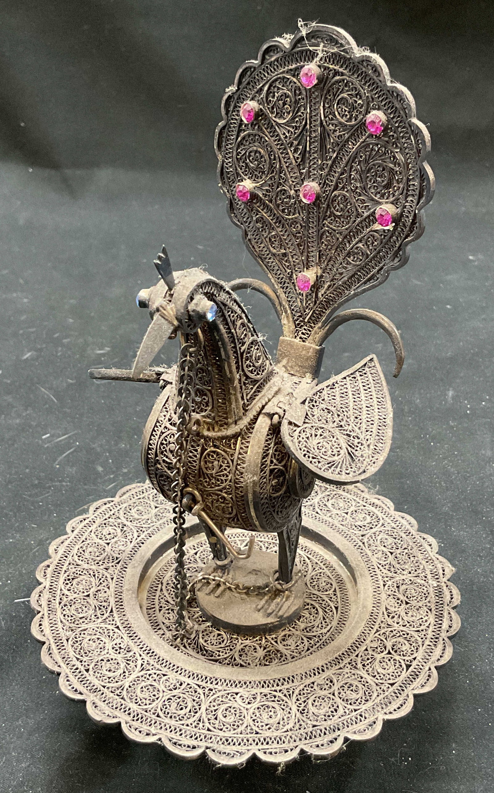 Vtg Silver Filigree Peacock Perfume Holder India: Vintage silver filigree peacock perfume holder. Tilted back head hinge connected with tiny perfume vile. Hook included to hold head securely on. There is a chain connected from the head to bottom near