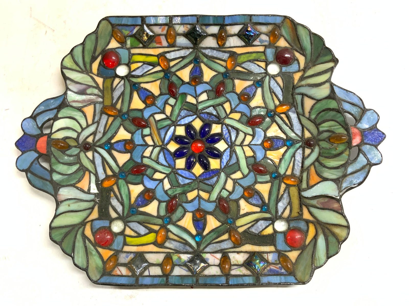 Vintage Stained Glass Tray Form Wall Hanging: Wall hanging has tray form. Piece is Vintage. Wall hanging is multi toned stained glass with floral and leaf detail. Piece has handles at sides. Measures approximately 18 inches long 13.5 inches wide.