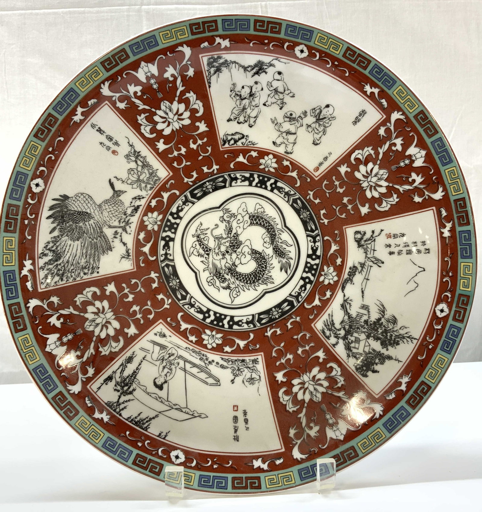 Chinese Dragon Phoenix Porcelain Charger Plate: Chinese Dragon Phoenix Porcelain Charger Plate Charger plate features a Chinese dragon in the center & other motifs surrounding the central dragon. Including images of children playing, landscapes & a