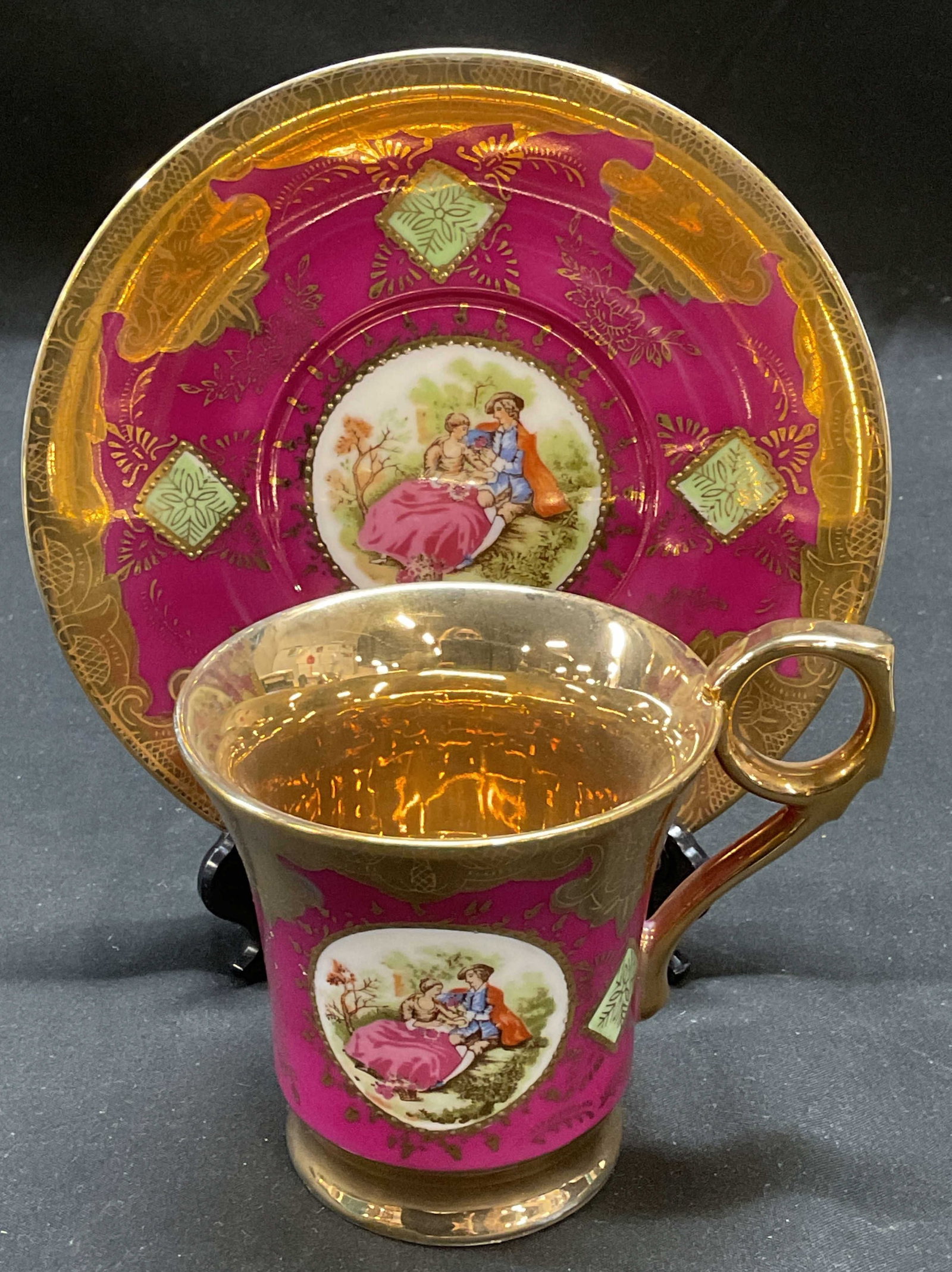 Vtg Arnart Porcelain Couple Teacup & Saucer: Vintage Arnart porcelain teacup and saucer in magenta with gilt decoration and hand painted detail. Signed. Saucer approx 5.75 inches, cup approx 3.25 x 3 inches. Some wear including scratching. Arnar