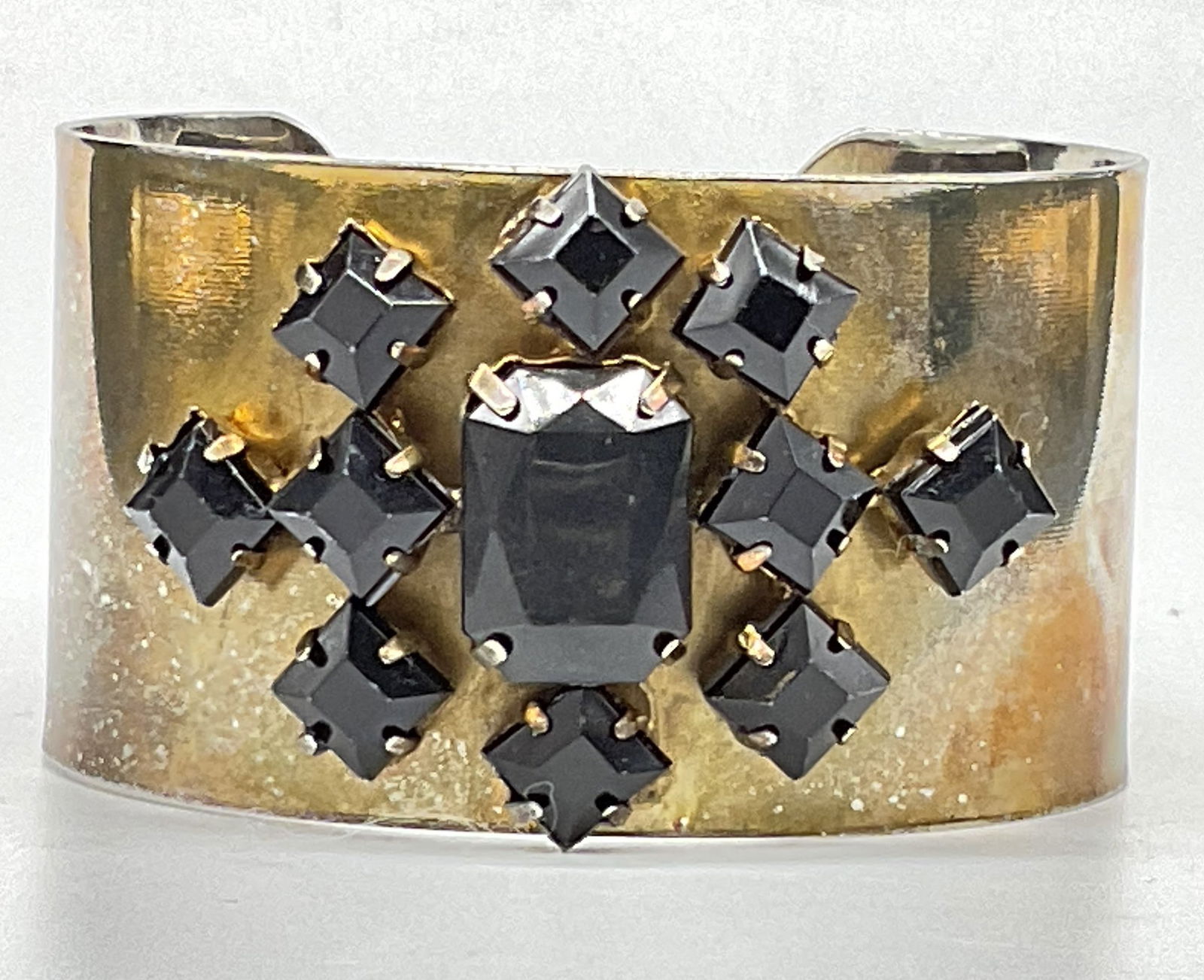 Vintage Bejeweled Gold Tone Metal Cuff Bracelet: Vintage Bejeweled Gold Tone Metal Cuff Bracelet. Raised prong set faceted black crystals to the obverse. Diameter measures approx. 2.5 inches at the widest point. Surface wear, chipping, and discolora