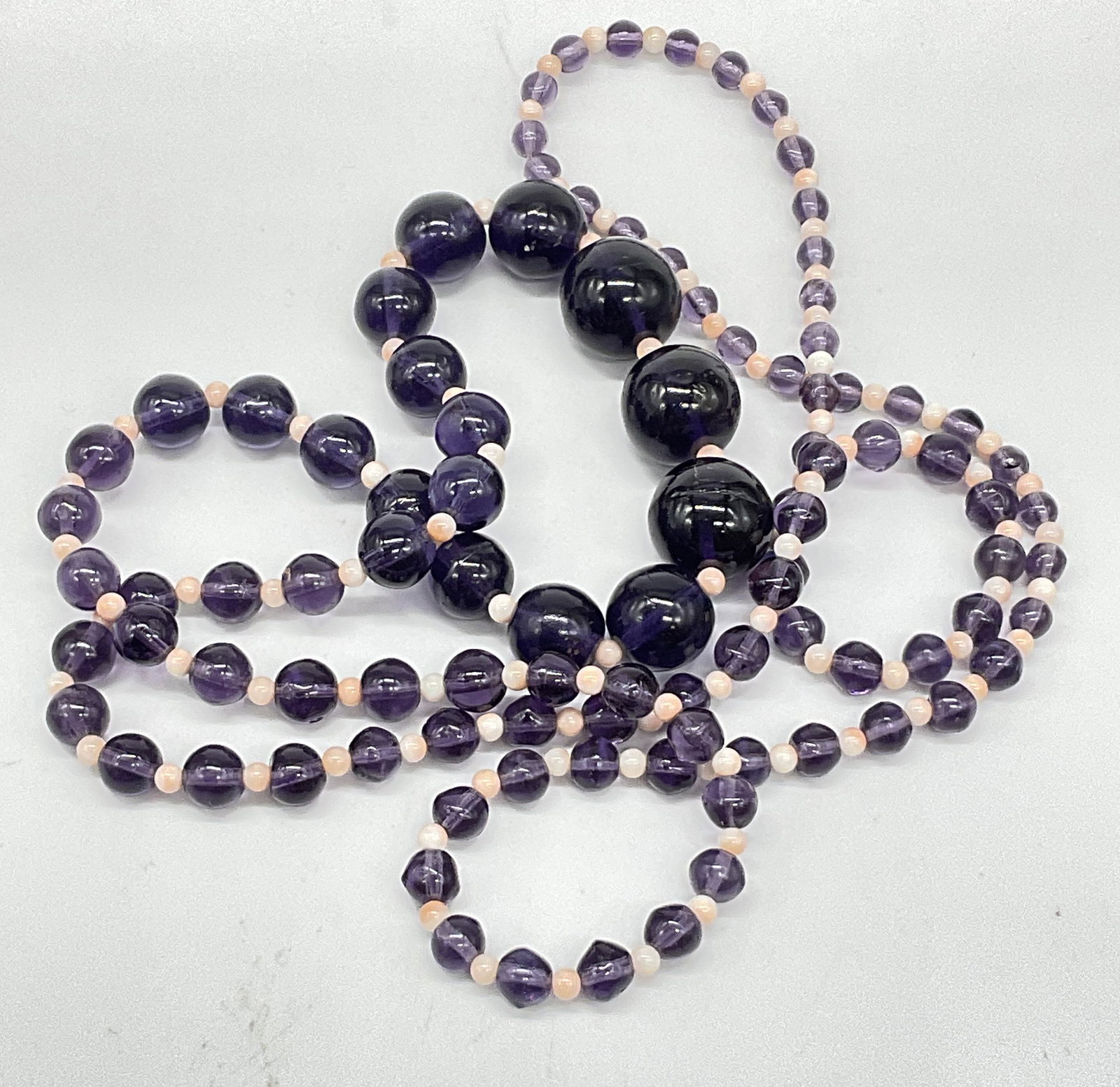 Purple & Pink Graduated Bead Necklace: Purple & Pink Graduated Bead Necklace. Crafted from composite and glass materials. Measured end to end approx. 19 inches. Surface wear consistent with age, use, and exposure. Chipping present. jewelry