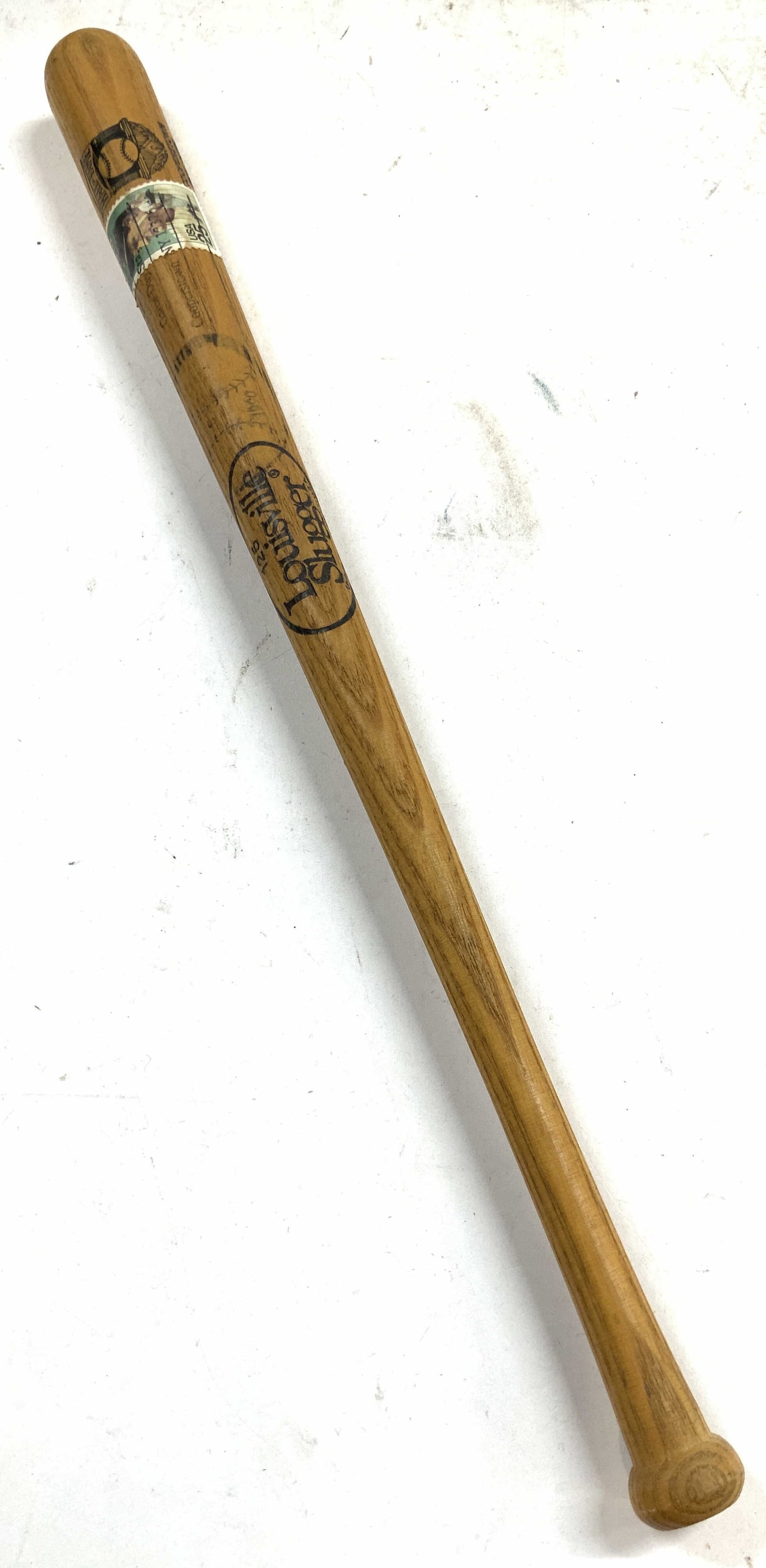 Louisville Slugger Miniature Baseball Bat: Baseball bat is tan toned and wooden. Piece is trademarked Louisville Slugger, & reads Cooperstown New York. Piece has vintage Lou Gehrig stamp. Miniature baseball bat measures approximately 16 inches
