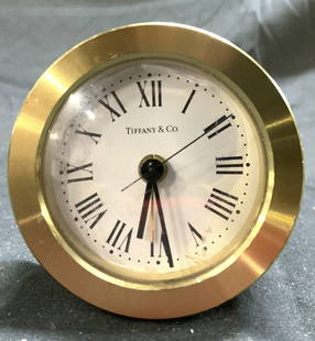 TIFFANY & CO Brass Desk Clk Monogrammed: Clock face reads TIFFANY & CO. Top of piece is monogrammed RI TRC DECEMBER 2 1997. Clock has white face with black toned hands and Roman numerals. Clock measures approximately 2.5 inches tall and wide