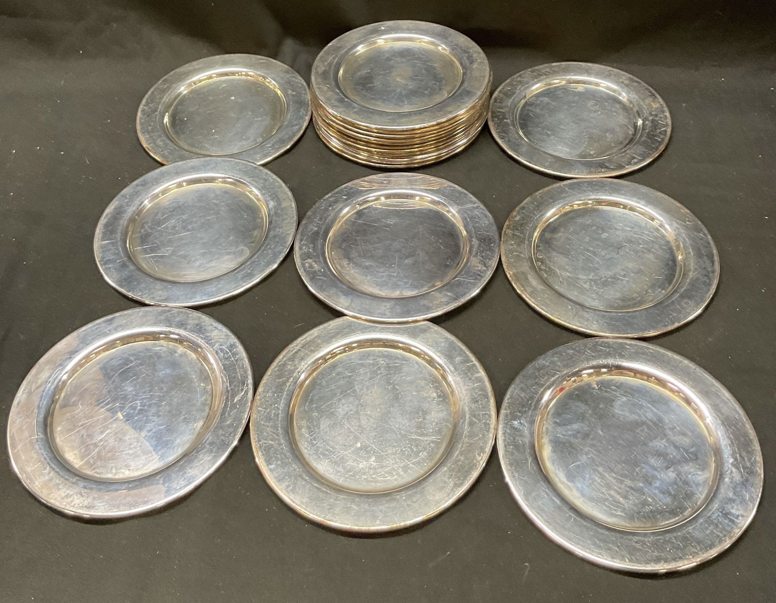 Set 19 Oneida Silversmiths Silver Charger: Set 19 Oneida Silversmiths silver charger plates. Small metal charger plates. Plates measure 6 inches in diameter. Signed on underside. Some surface wear consistent with exposure, some scratching and