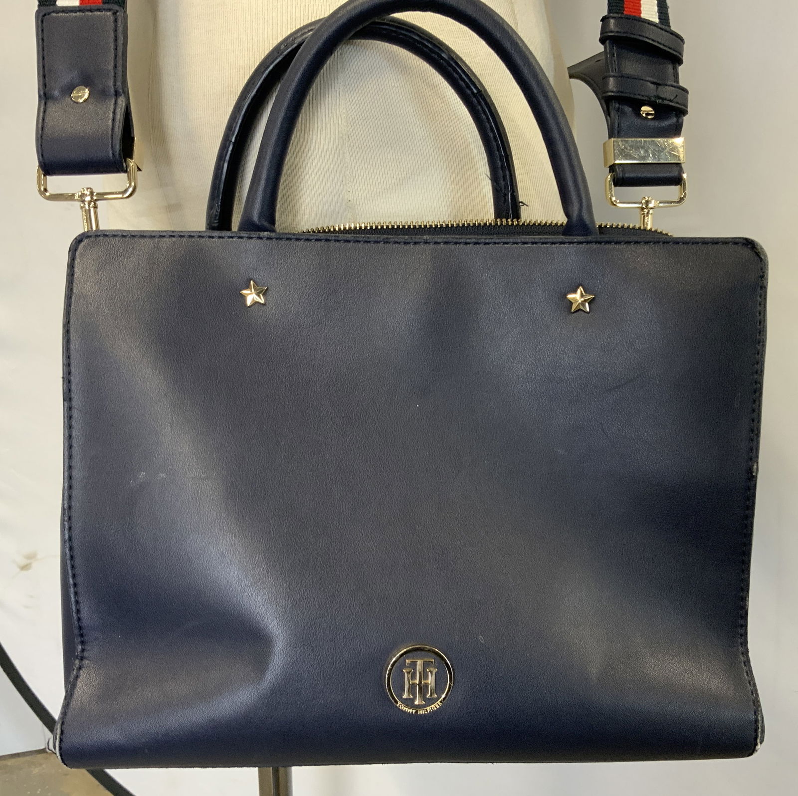 TOMMY HILFIGER Navy Faux Leather Satchel Bag: Handbag features a top handle & a detachable, striped shoulder strap. Bag has gold-toned hardware & two star studs on the front. Signed & marked. Surface wear consistent to age, use & exposure. Measur