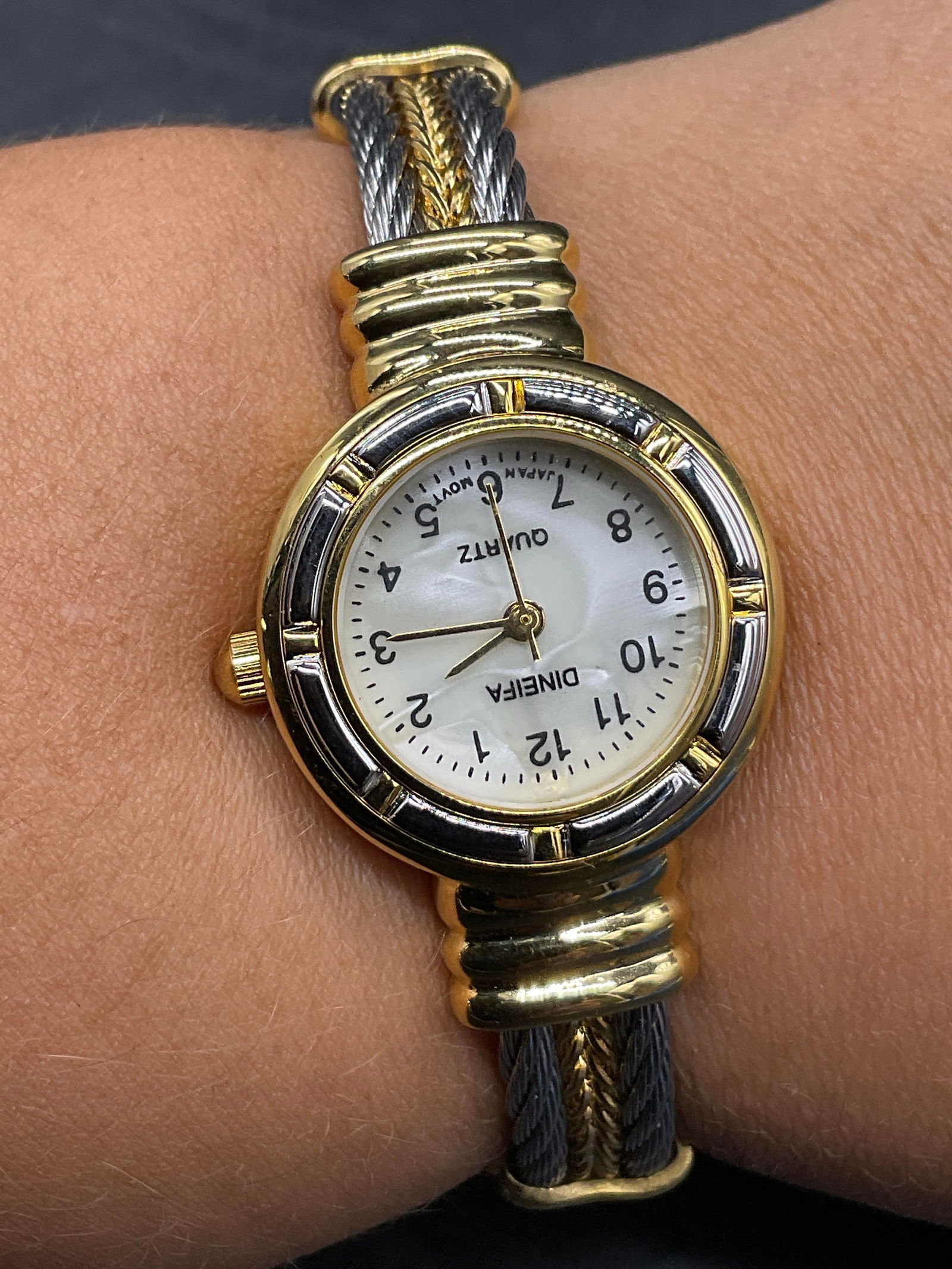 DINEIFA QUARTZ Gold & Silver Tn Metal Wristwatch: Vintage DINEIFA QUARTZ Gold & Silver Tone Metal Wristwatch. Diameter measures approx. 2.25 inches. Obverse reads DINEIFA QUARTZ, Japan. Pearlescent watch face. Reverse reads Steel Back. Not tested for