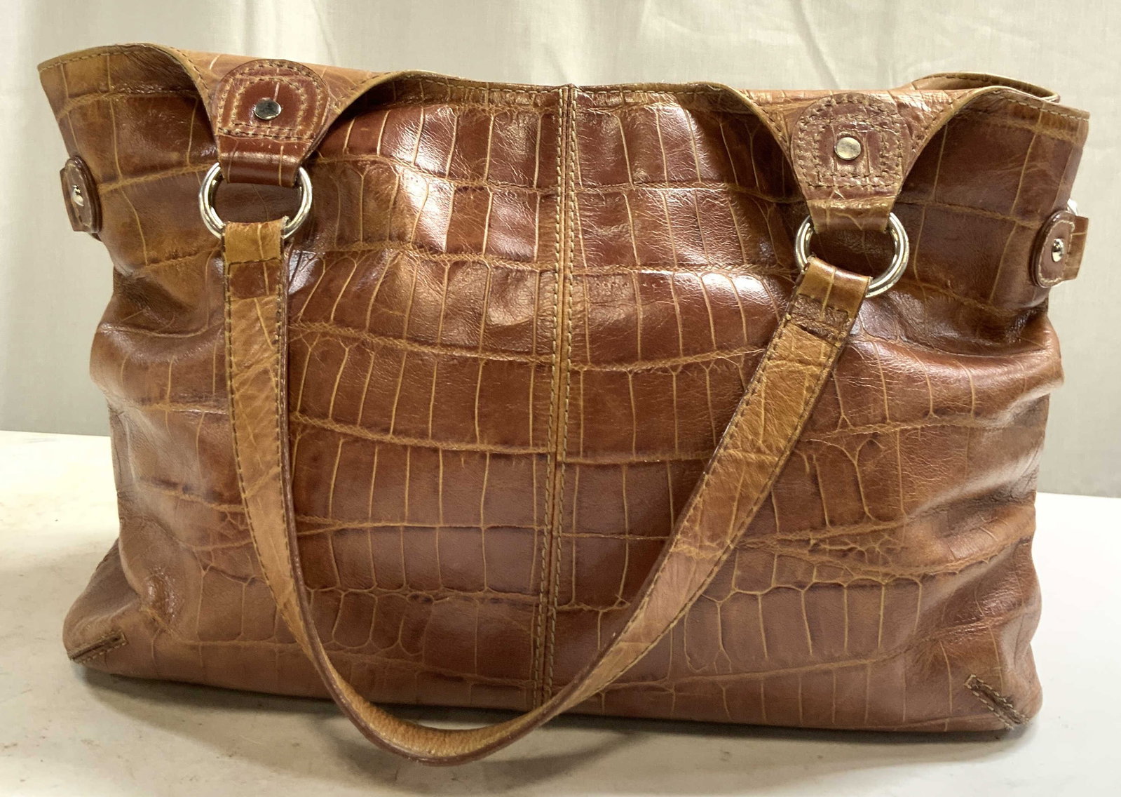 BANDOLINO Womens Leather Purse Beige: Tag on interior reads BANDOLINO. Womens bag IS beige toned and leather. Piece has silver toned metal hardware, interior has 3 zippered pockets. Measures approximately 16.5 inches tall hanging from str