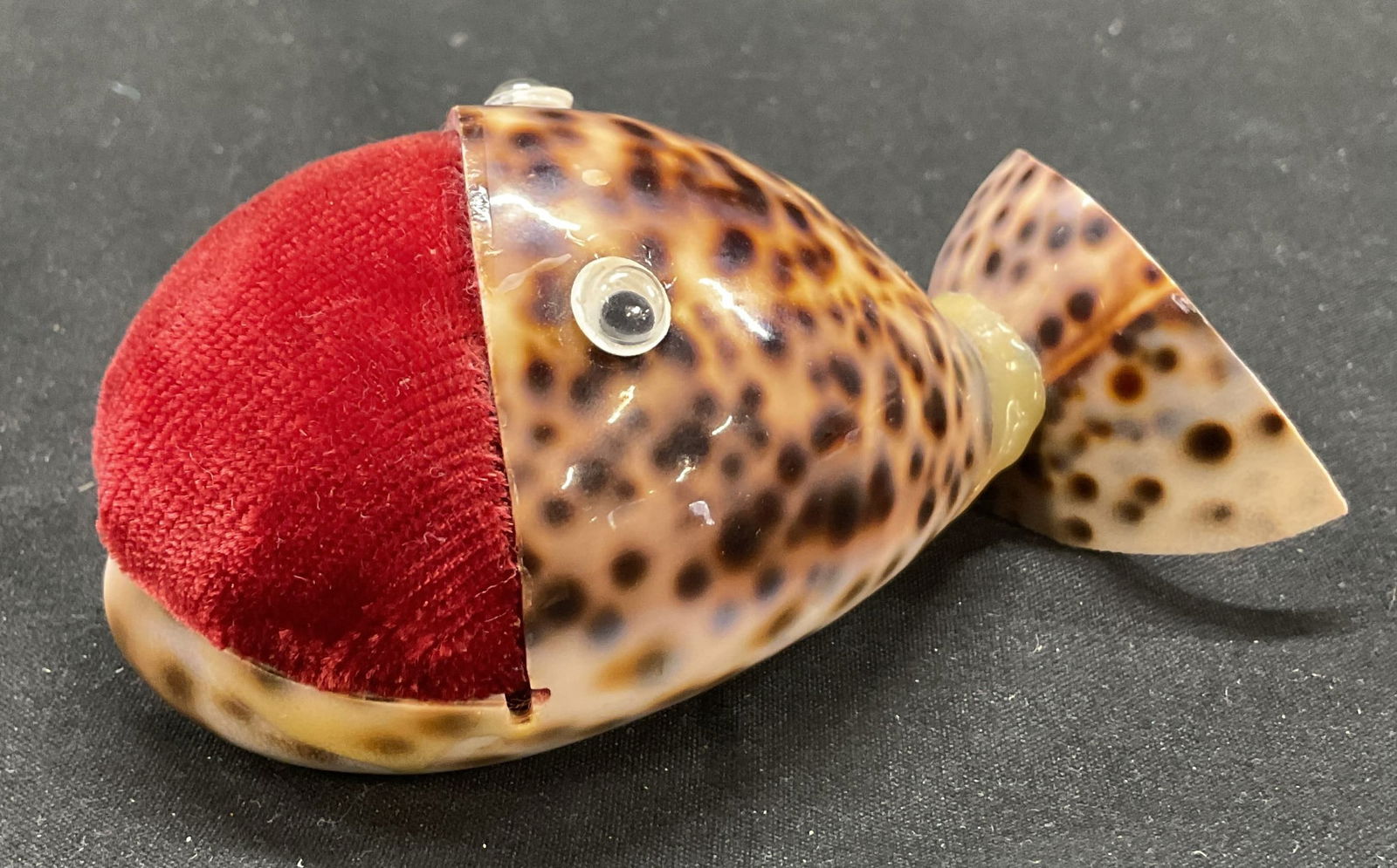 Vtg Whale Tiger Leopard Conch Shell Pin Cushion: Vintage whale tiger leopard conch shell pin cushion. Hand made, Velvet red pin cushion encased by tiger leopard conch shell with googly eyes. 3.5 x 2 x 1.5 inches. Some surface wear consistent with ex