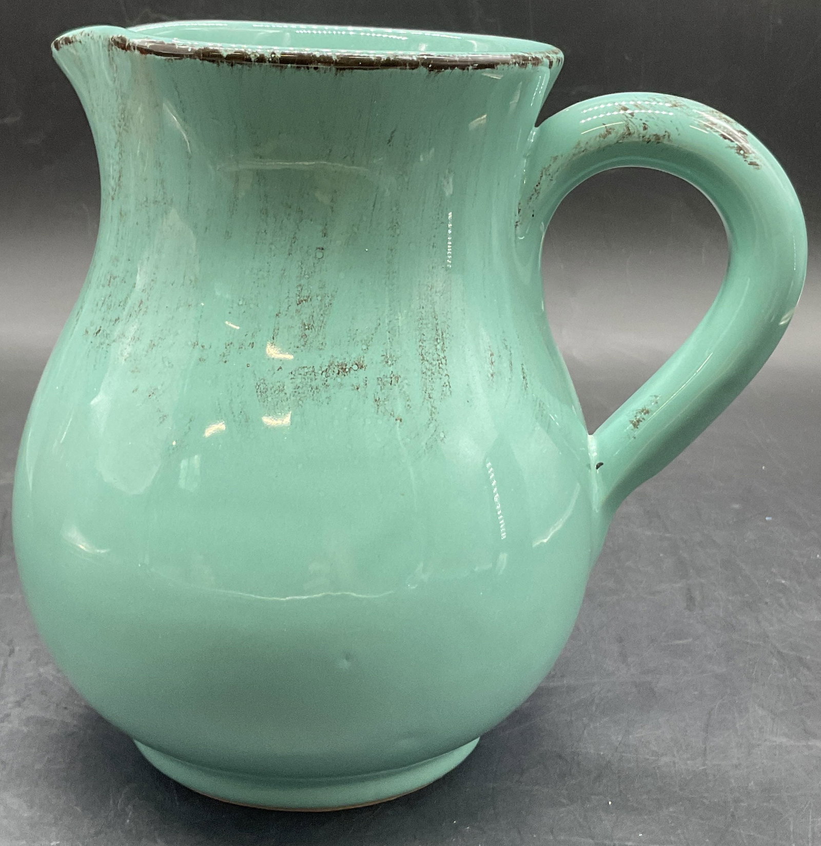 Vintage Handmade Teal Pottery Pitcher, Italy: Vintage Handmade Teal Pottery Pitcher. Brushed glaze is teal and black tones. Underside and sticker both read MADE IN ITALY or MADE ITALY. Measures approx. 6.75H x 6.5W in. Measurement includes handle