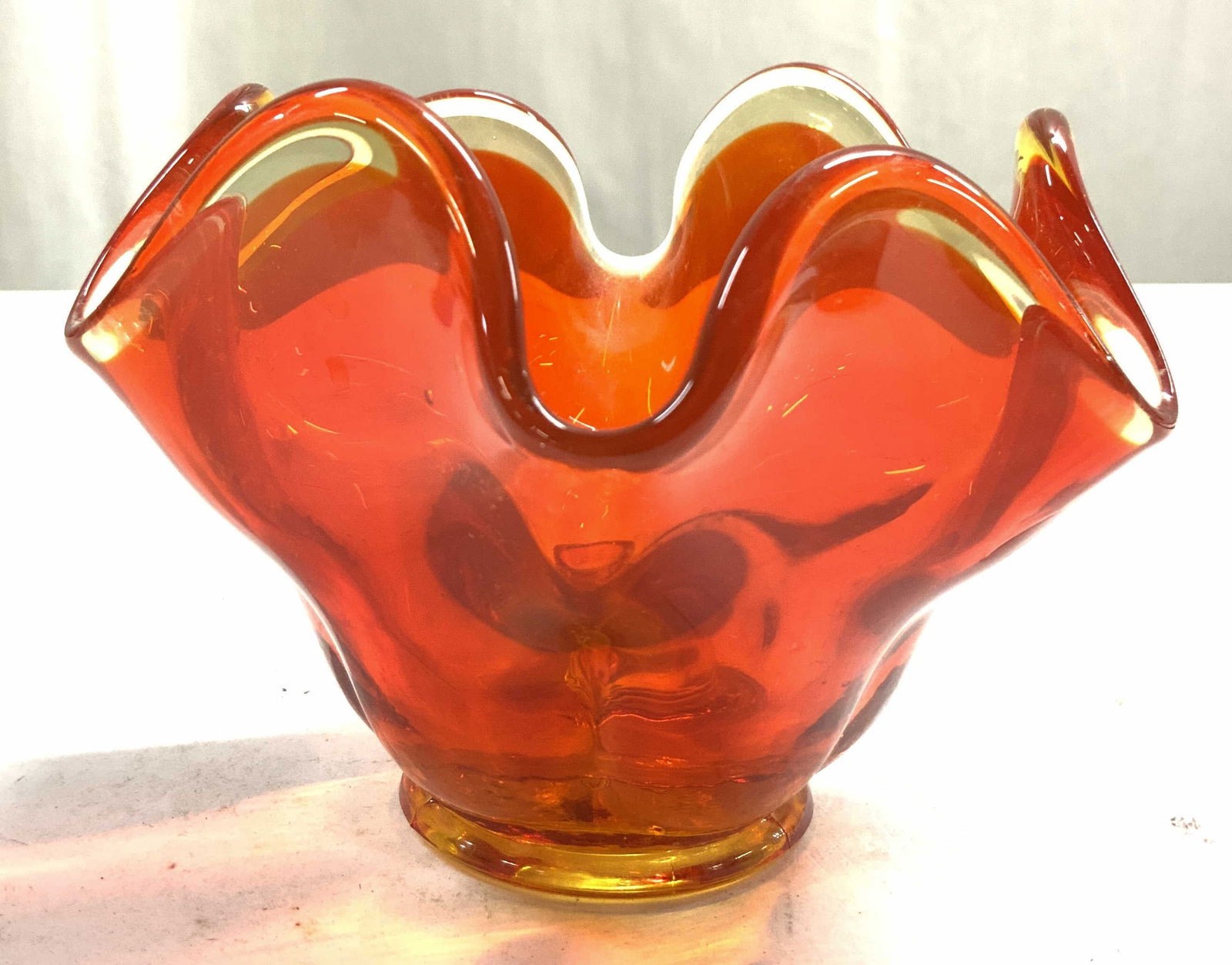 Handkerchief Amberina Glass Candle Holder: Candle holder is orange toned. Piece has handkerchief form. Candle holder is footed. Piece is glass. Possibly hand blown. Measures approximately 5.25 inches wide 3.5 inches tall Candle holder, candles