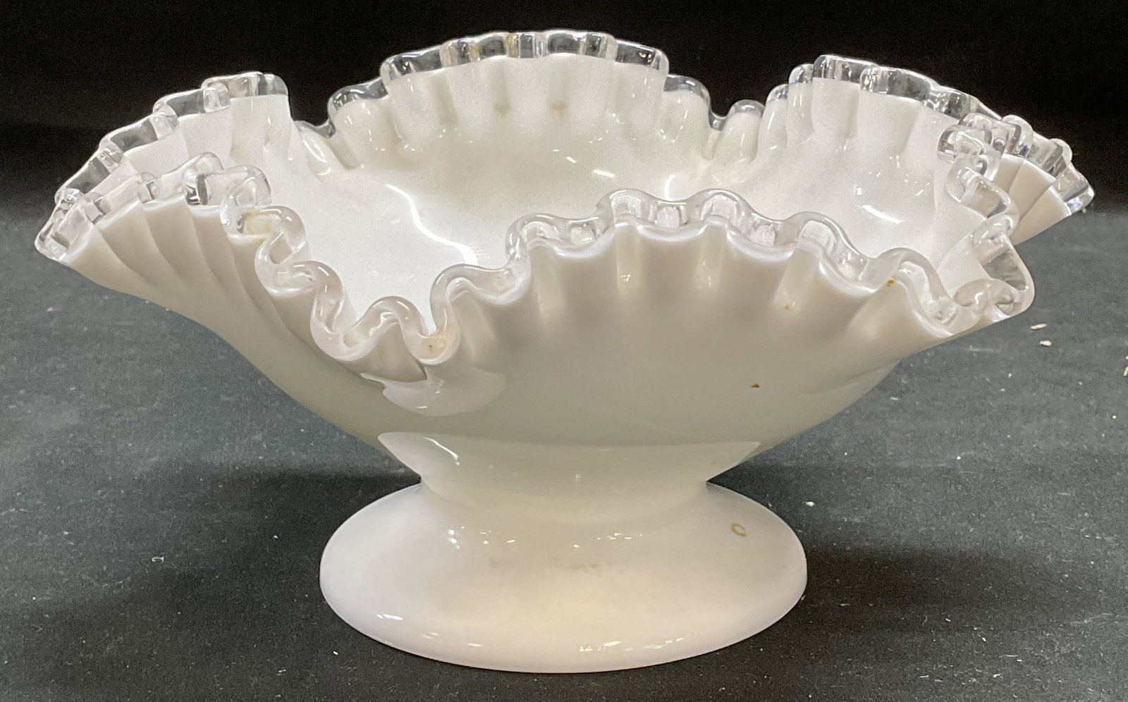 Vintage Milk Glass Footed Handkerchief Bowl: Vintage milk glass bowl. Footed with handkerchief and clear glass rim. Thick walled glass, piece has weight. Style of Fenton, no visible marks. Measures approx 8 x 4 inches. Some wear consistent with 