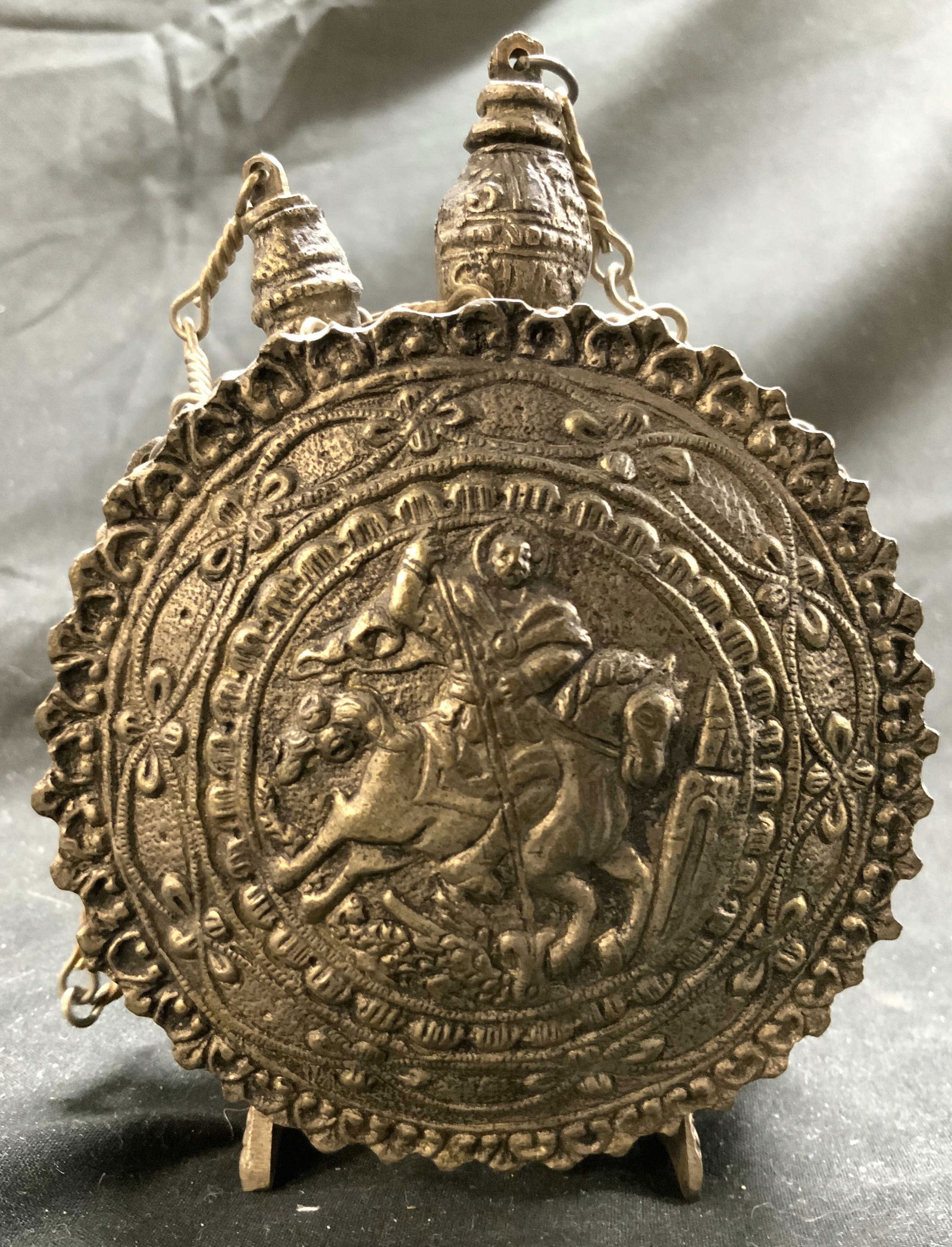 Antq Russian Balkan Gunpowder Flask: Gunpowder flask is antique. Piece is crafted from white metal. Flask has depiction of figure riding a horse in addition to other intricate details. Flask has 2 bird form feet. Piece measures approxima