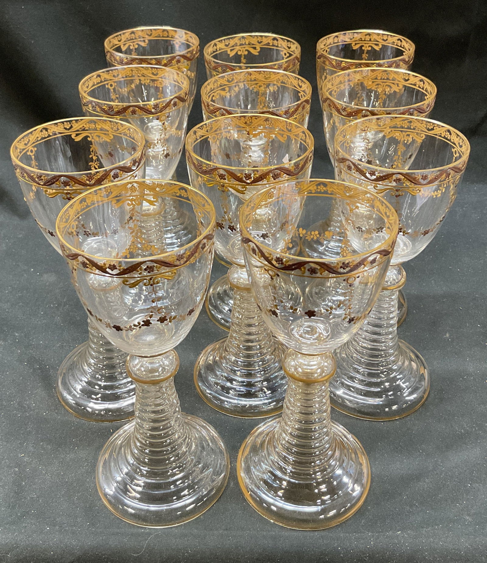Set 11 Baccarat Medicis Gold Rim Crystal Glasses: Set 11 Baccarat Medicis gold rim crystal glasses. Floral pattern. Wine glass goblet. Flared bottom. 7 x 3 inches. Some surface wear consistent with exposure. Gold rim glasses, drinking glasses, crysta