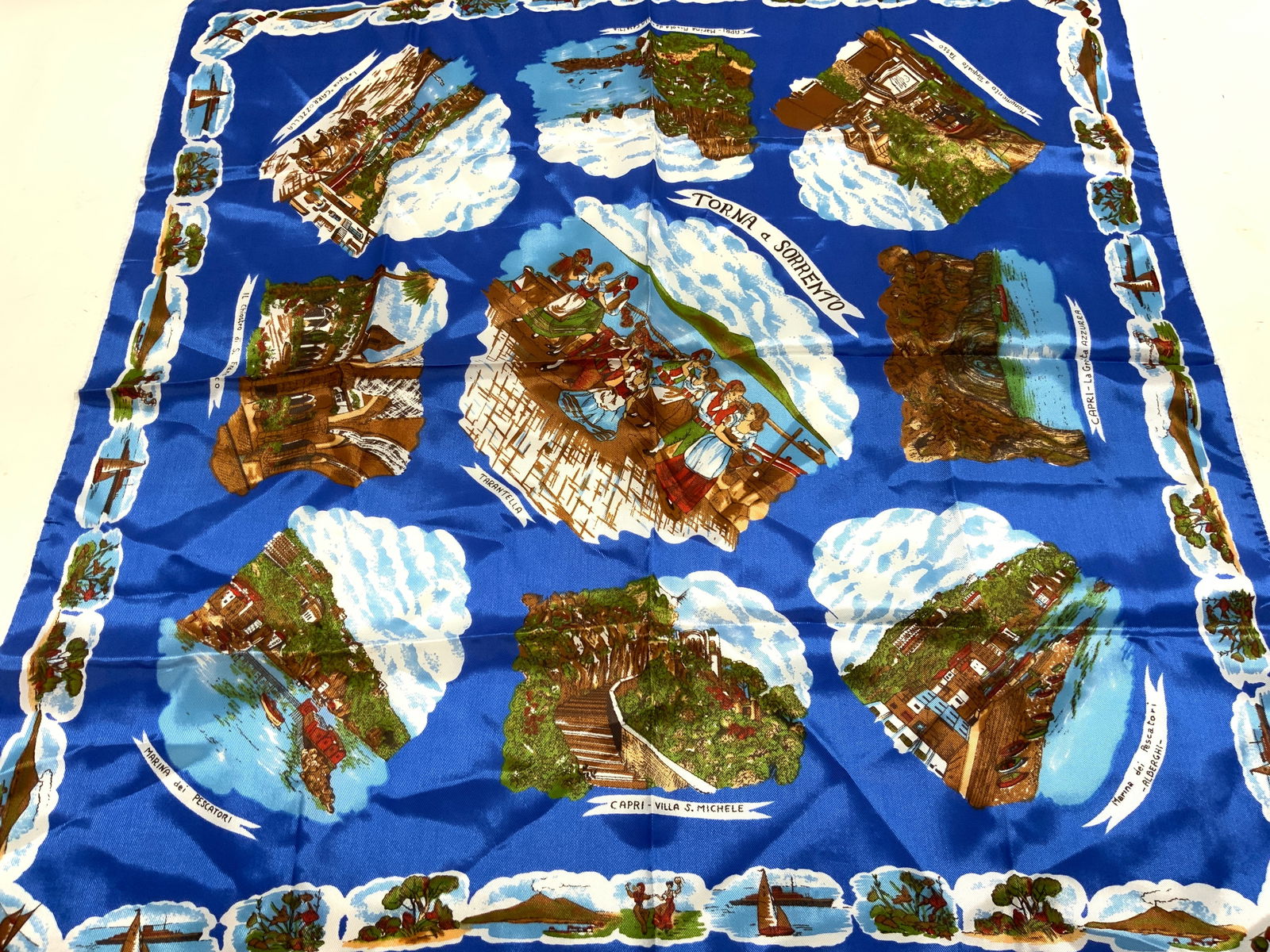 Torna a Sorrento Scenic Blue Silk Scarf: Torna a Sorrento Scenic Blue Silk Scarf Scarf appears to be silk & features scenic illustrations around the edges & dancing figures in the center. Surface wear consistent to age, use & exposure. Measu
