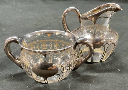 Set 2 Vtg Silver Overlay On Glass Creamer Cruet: Set 2 vintage silver overlay on glass creamer cruet. Cruet with 2 handles, small creamer. Geometric silver overlay designs. Cruet measures 2.25 x 5 inches. Some surface wear consistent with exposure.