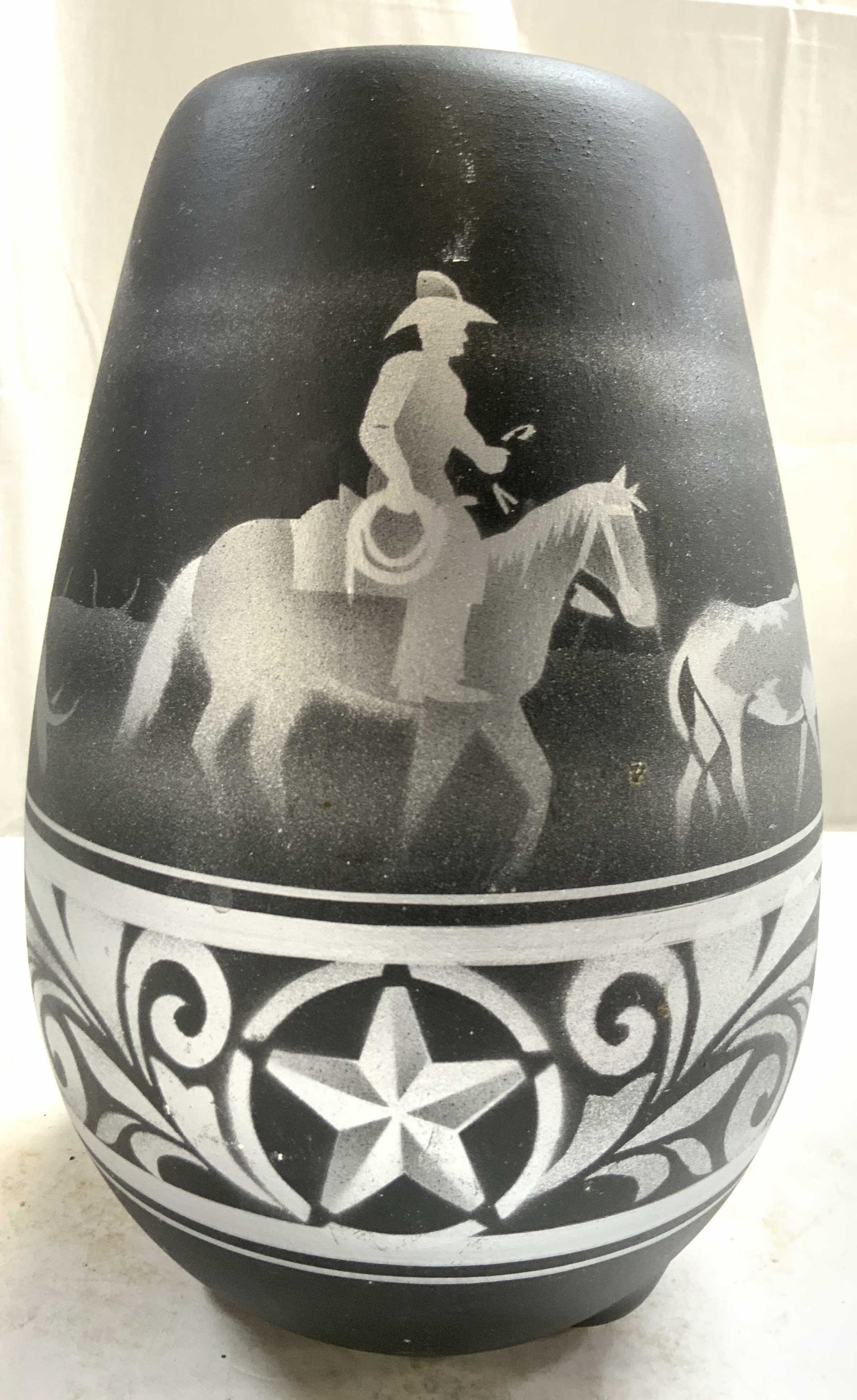 DINE Signed Vtg Native American Southwest Vase: Underside is signed DINE. Native American southwest pottery vase. Piece is black with silver toned depictions of a figure riding horseback following a steer. Vessel appears to be vintage. Piece measur