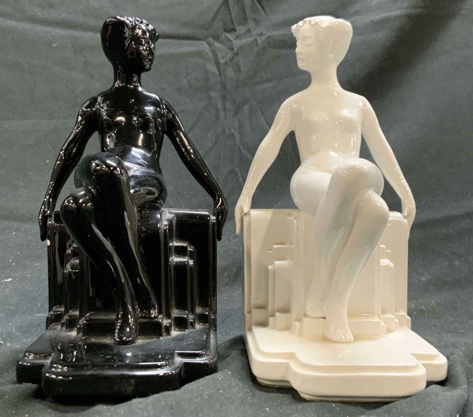 FITZ & FLOYD Female Nude Bookends Blk & Wht: Backsides of bookends are marked FITZ & FLOYD. Lot includes 1 white and 1 black toned bookend. Each bookend depicts a seated female nude figure. Bookends appear to possibly be porcelain. Each measures